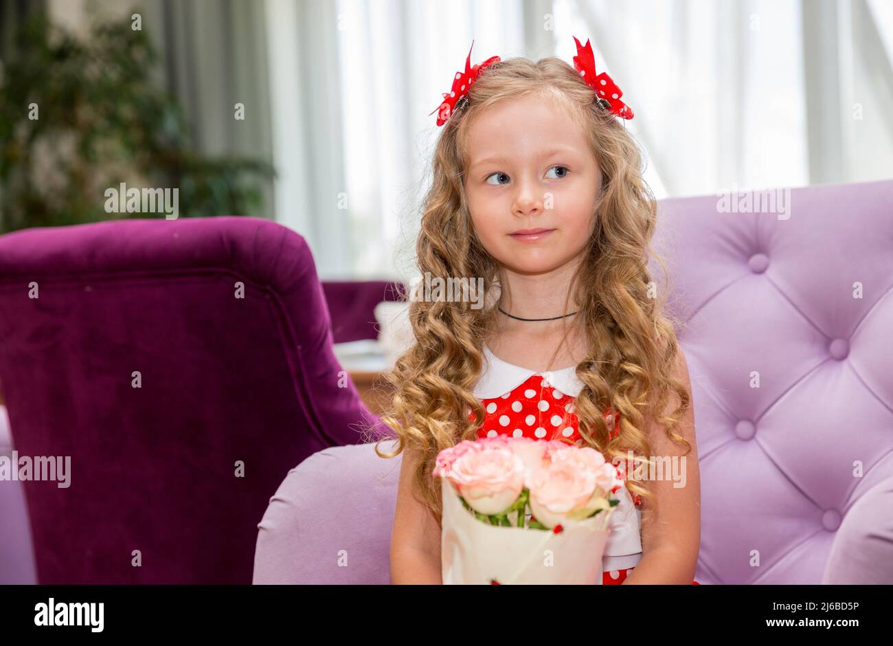 Happy kid girl celebrating birthday party with bouquet of flowers in cafe. Child name-day. Stock Photo