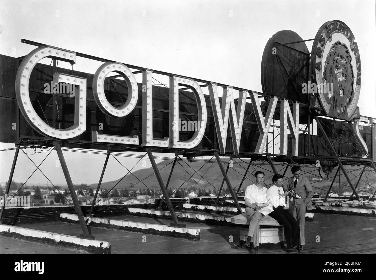 GOLDWYN STUDIOS SIGN (with Logo later used by MGM) on roof of Samuel Goldwyn's studio in Culver City California in 1921 with at left future director ROBERT FLOREY who at the time had just arrived in Hollywood as a Correspondent for a French Film Magazine Stock Photo