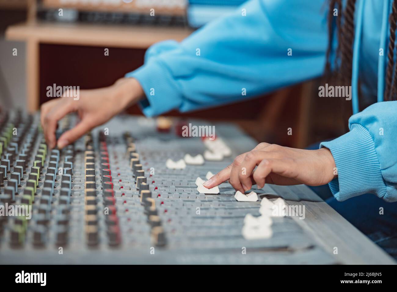 Female sound engineer, musician producer hands using mixing board and