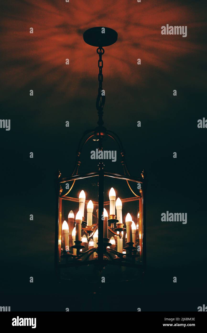 A traditional colonial chandelier hanging from the ceiling creating the evening glow with a red