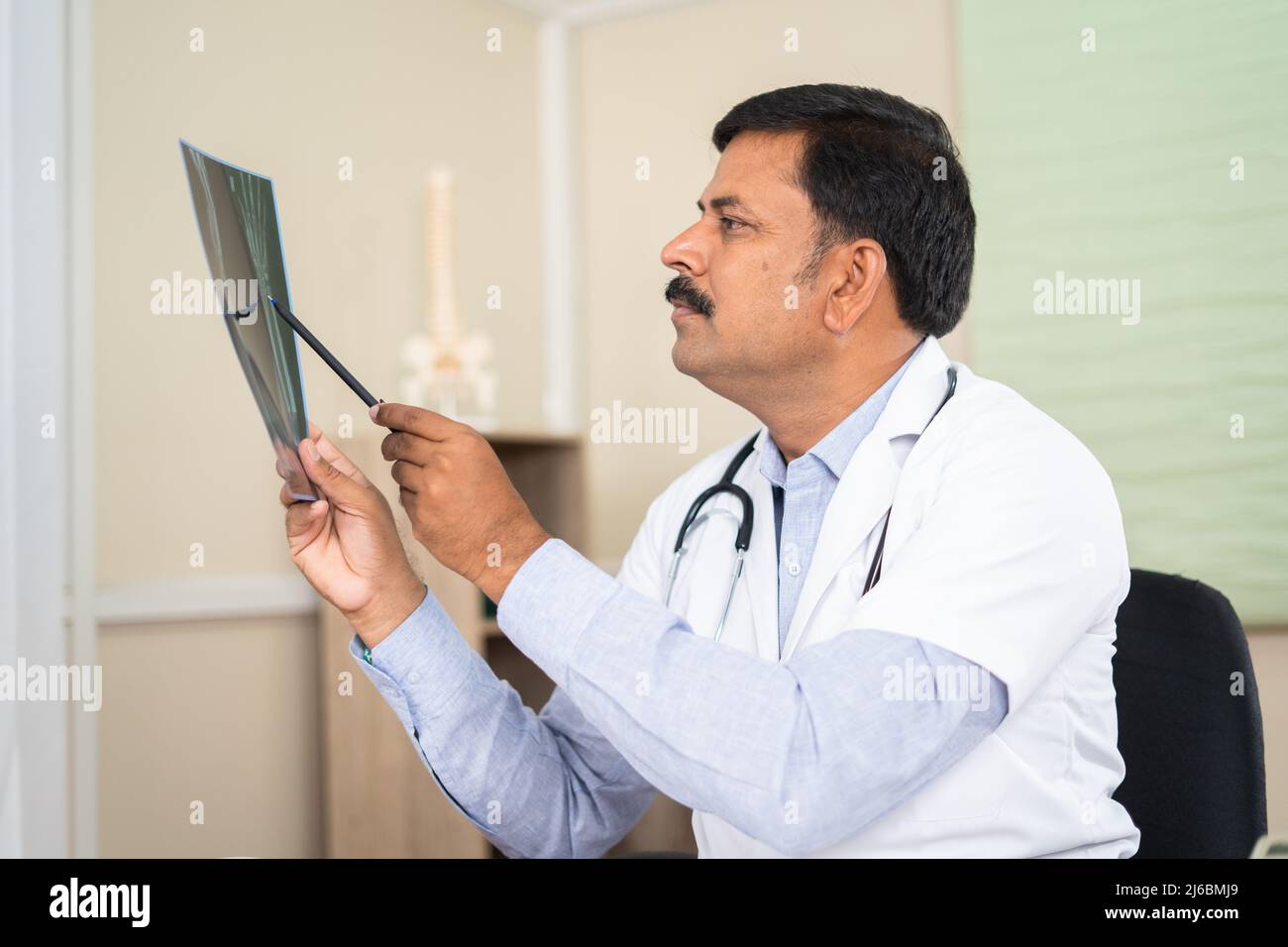 Doctor in concentration at hospital analysing x ray report - concept of healthcare treatment, diagnosis and medical expertise Stock Photo