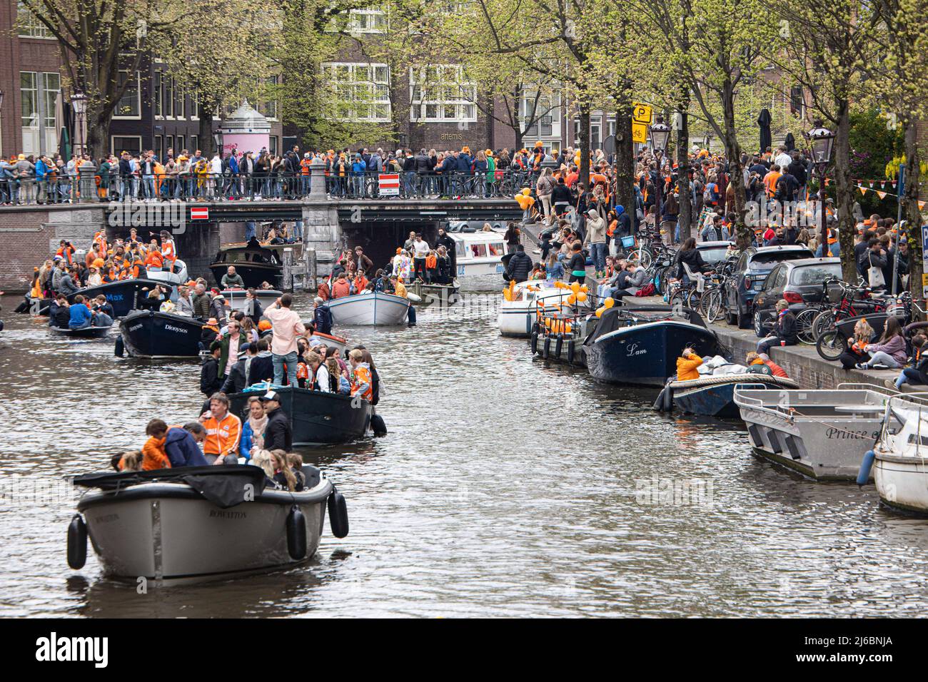 People seen on the boats in the canals of Amsterdam during the King's Day celebration. King's Day known as Koningsdag is an orange filled celebration for the king's birthday, a national holiday full of events across the country. Thousands of local revellers and tourists visited Amsterdam to celebrate and party around the canals while wearing orange clothes and the boats doing a parade in the water canals. Stock Photo