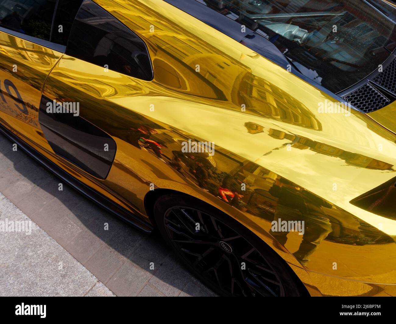 London, Greater London, England, April 23 2022: Gold wrapped sports car with black wheels in an abstract style shot. Stock Photo