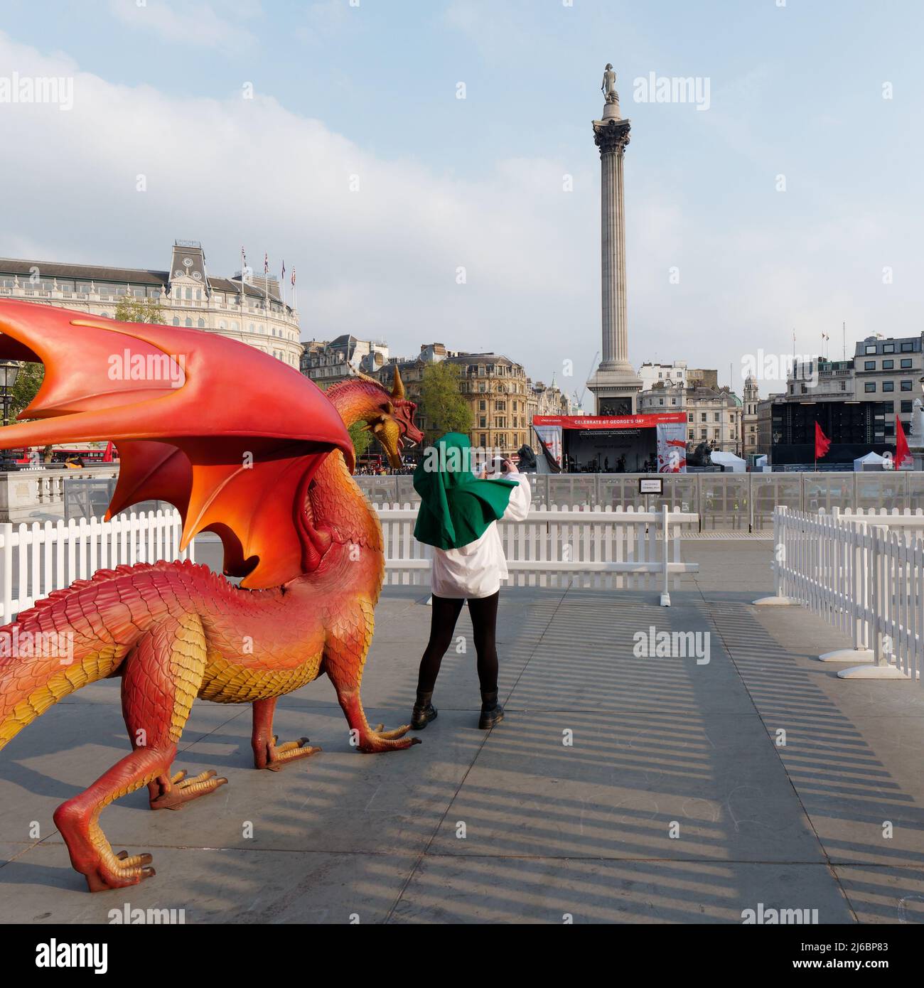 London, Greater London, England, April 23 2022: Lady in an outfit taking a selfie with the Dragon in Trafalgar Square on St Georges Day. Stock Photo