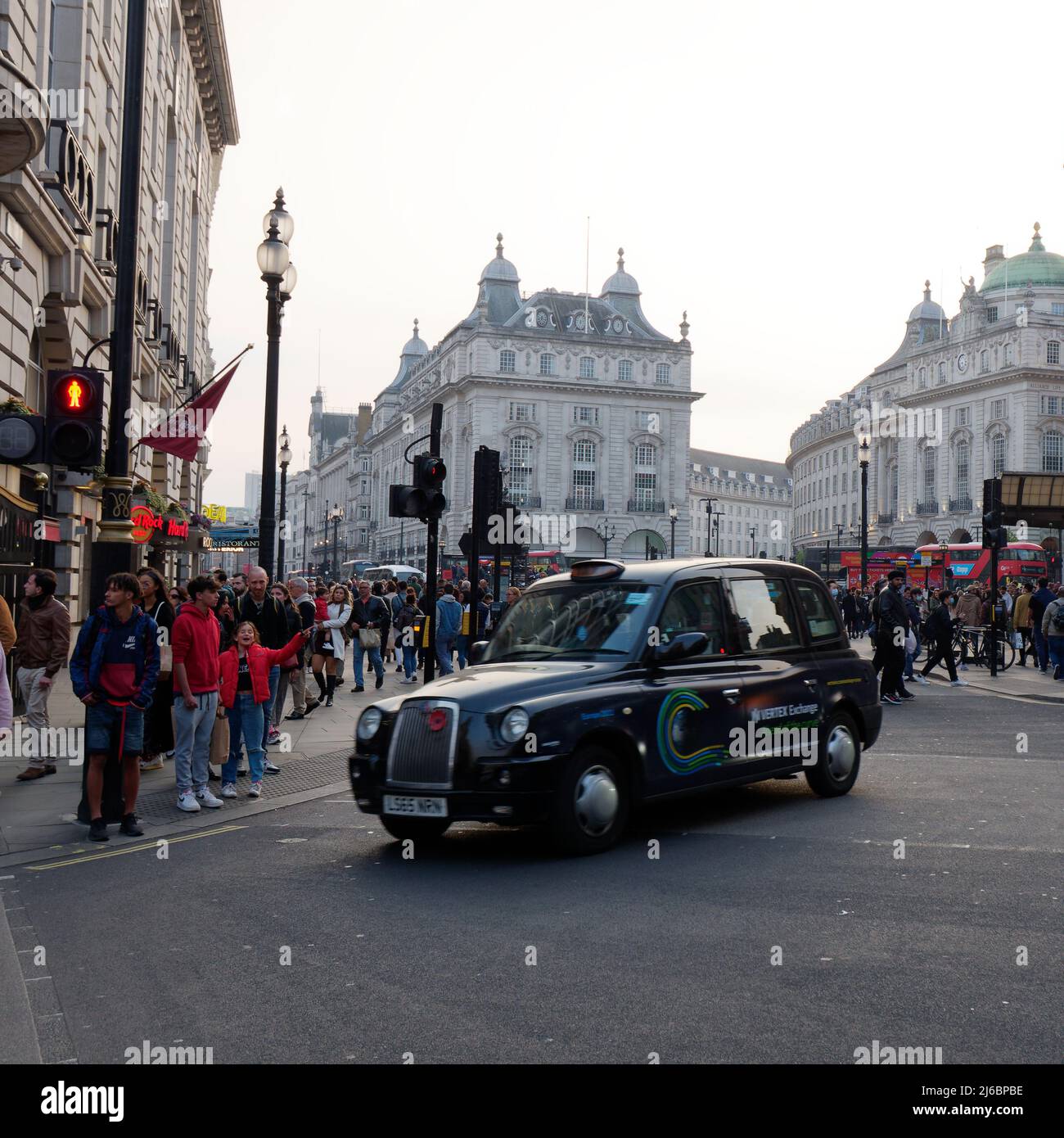 London, Greater London, England, April 23 2022: Taxi aka Cab in Piccadilly Circus as people wait at the pedestrian crossing. Stock Photo