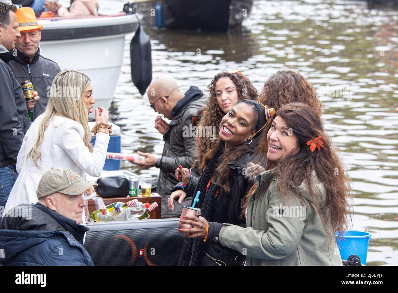 April 27, 2022, Amsterdam, Netherlands: People seen on a boat in the canals of Amsterdam during the King's Day celebration. King's Day known as Koningsdag is an orange filled celebration for the king's birthday, a national holiday full of events across the country. Thousands of local revellers and tourists visited Amsterdam to celebrate and party around the canals while wearing orange clothes and the boats doing a parade in the water canals. (Credit Image: © Nik Oiko/SOPA Images via ZUMA Press Wire) Stock Photo