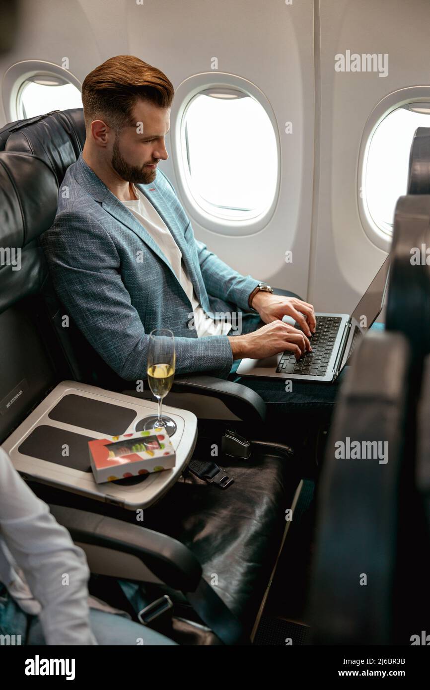 Bearded man using portable laptop in airplane Stock Photo