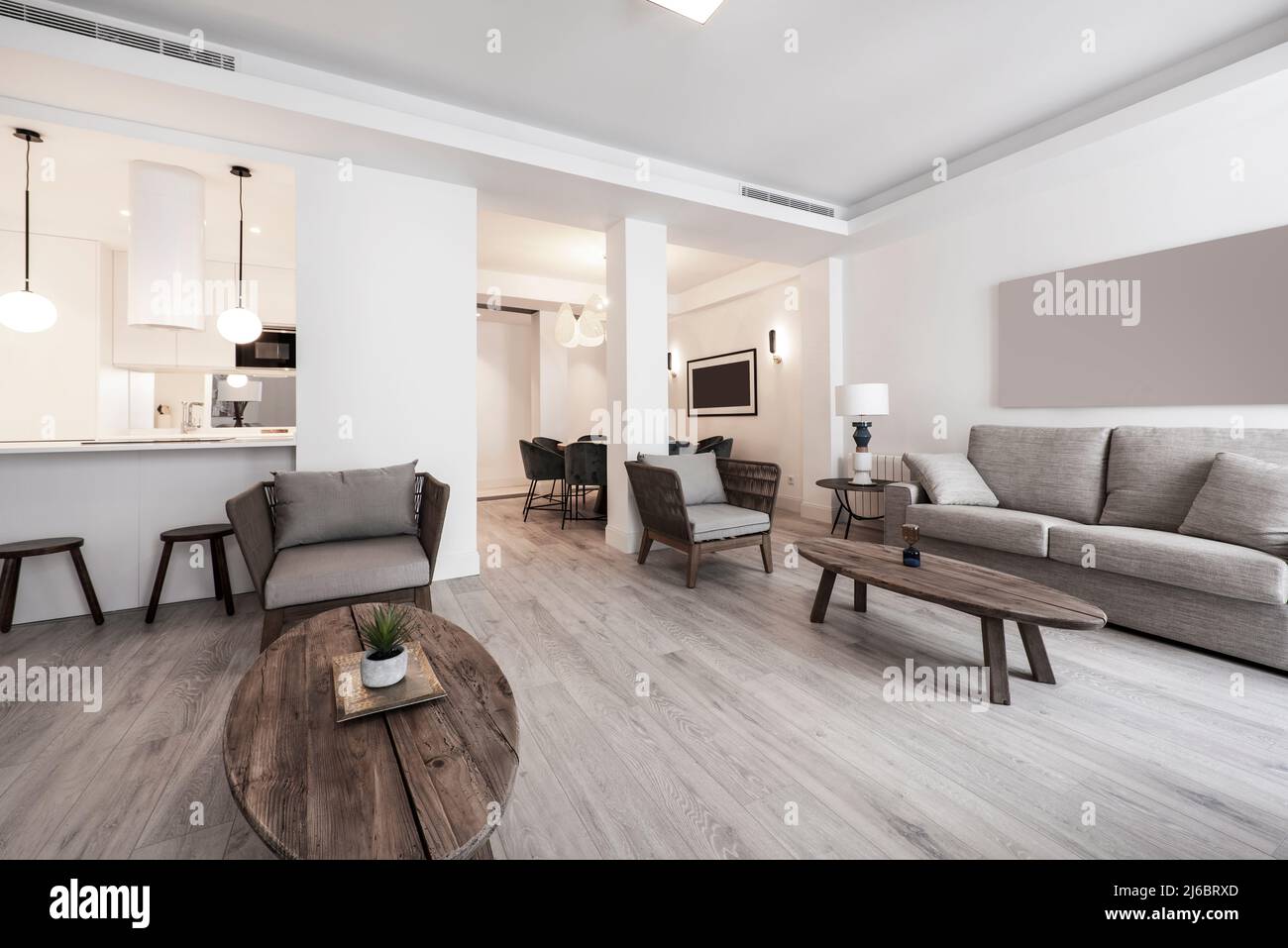 Large living room with twin wooden tables, wicker and gray fabric sofas