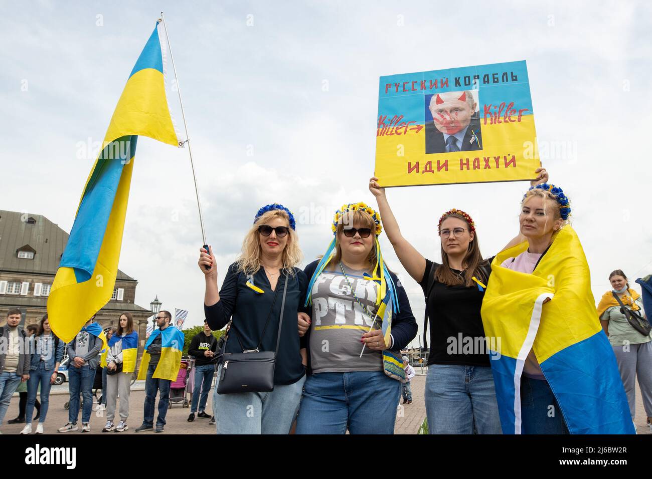 30 April 2022, Saxony, Dresden: Four women in the colors of Ukraine and with flags and a likeness of Putin on a banner in Cyrillic. Counter-event against pro-Russian rally with the title: 'Solidarity with the people of Ukraine! All together against Putin's war of aggression!'. >Release of photo use of all women granted<. Photo: Daniel Schäfer/dpa Stock Photo