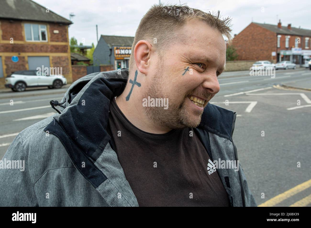 Young man with cross tattoo during a 6 months probation near the Wakefield Probation Office, West Yorkshire, England. Stock Photo