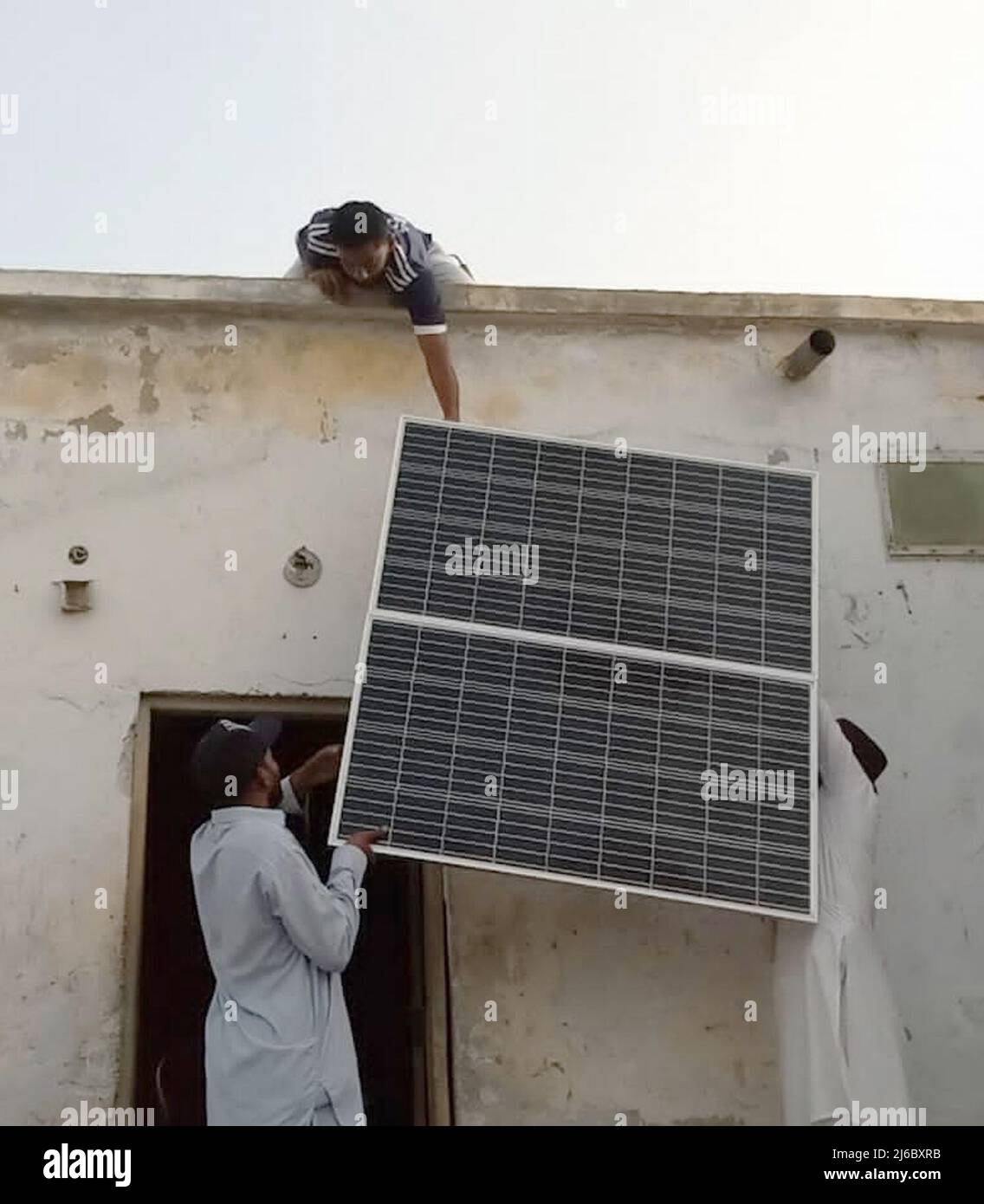 (220430) -- GWADAR, April 30, 2022 (Xinhua) -- Workers install a China-donated solar panel at a house in Gwadar, Pakistan, March 14, 2022.  TO GO WITH 'Feature: Chinese aid illuminates houses, helps fishermen in Pakistan's Gwadar' (Str/Xinhua) Stock Photo