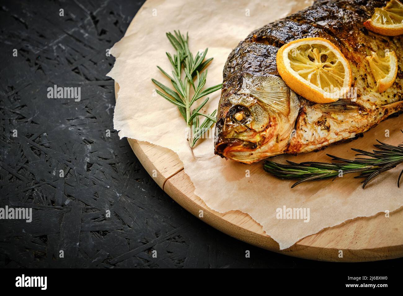 Baked fish in oven with lemon and rosemary laid out cutting board and