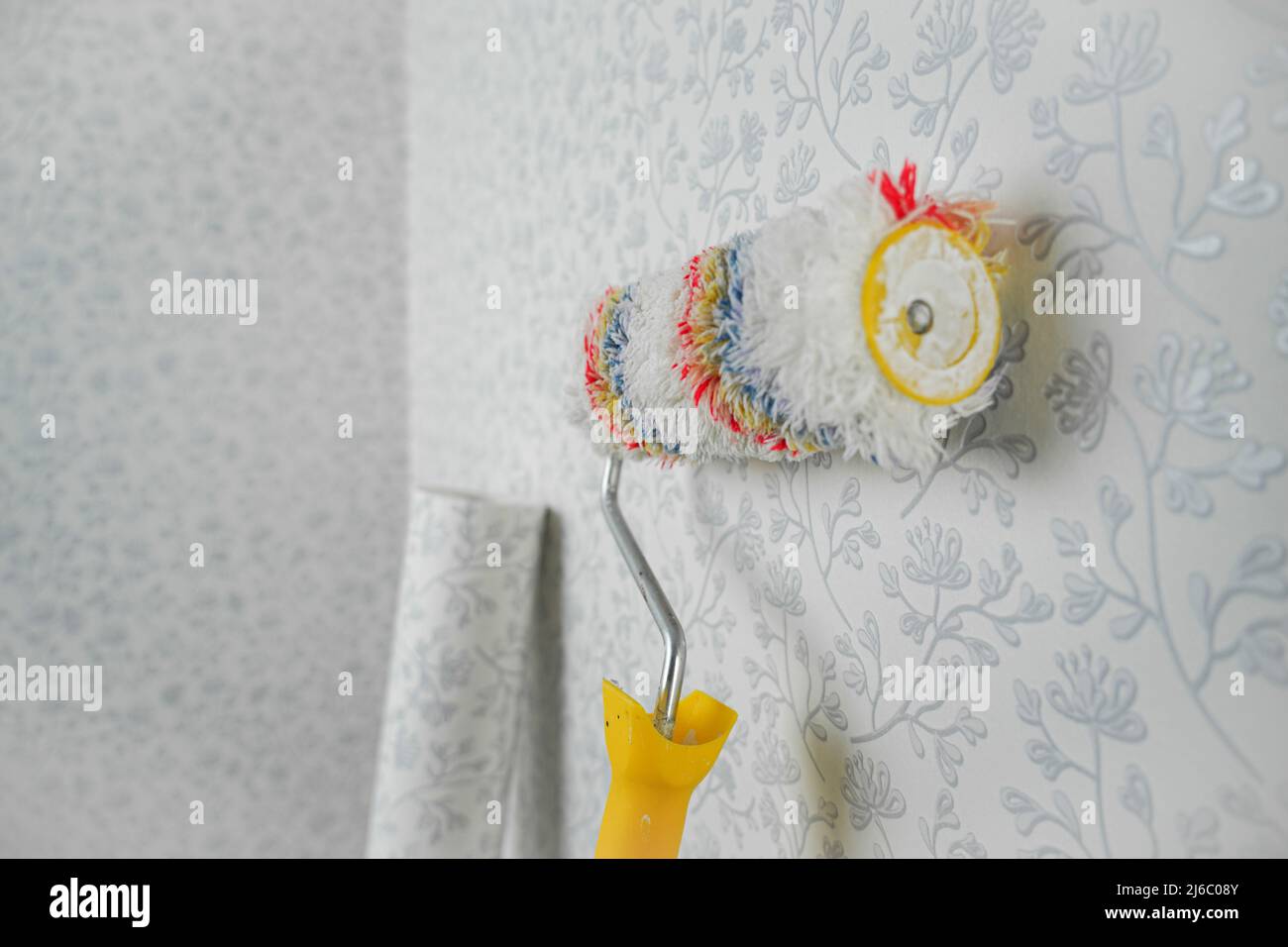 A long-haired roller stands near the wall for whipping wallpaper, a roller with a long handle Stock Photo