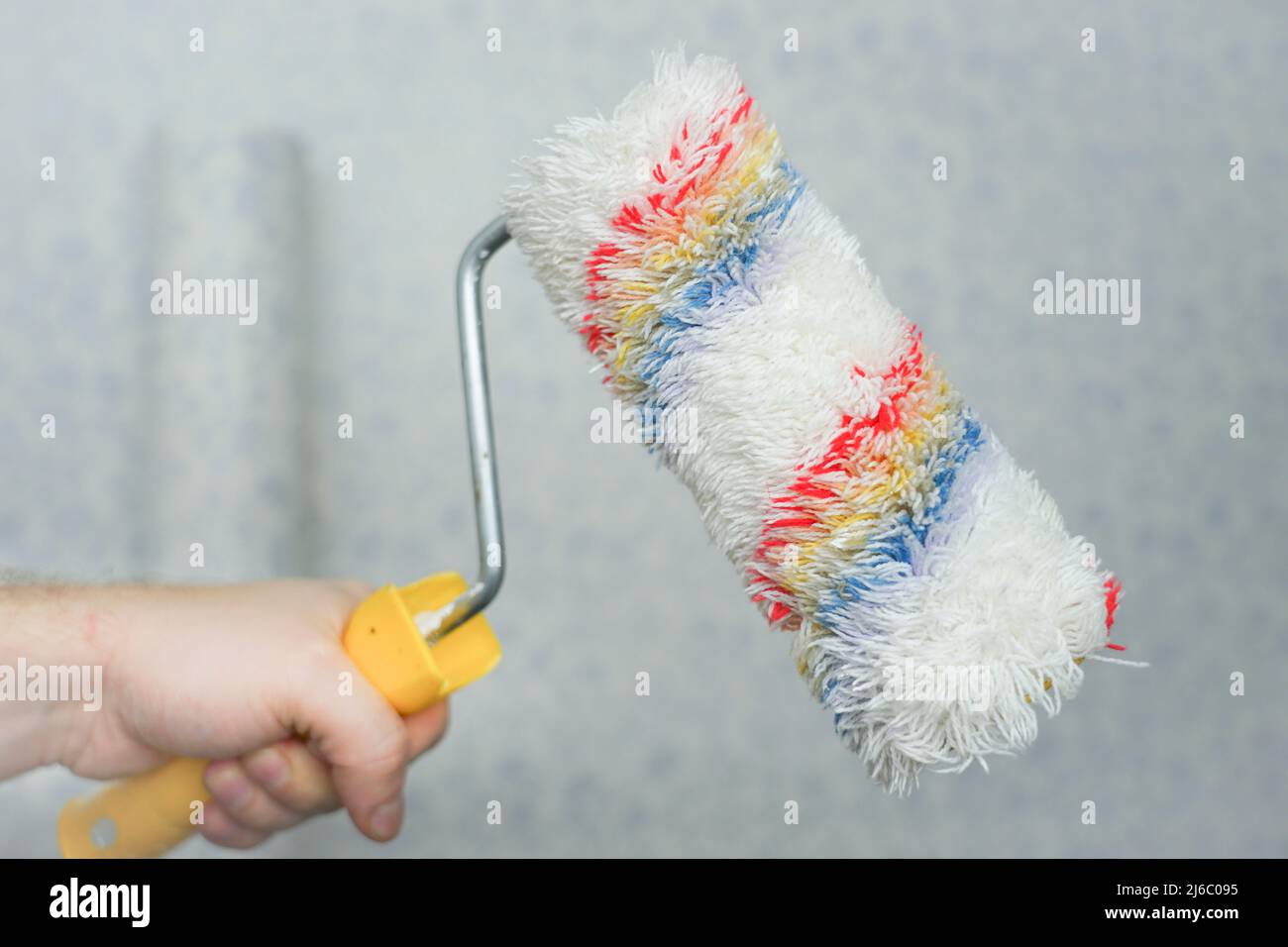 Hand holds a roller for painting the walls. Soft roller for wallpapering and textured application Stock Photo