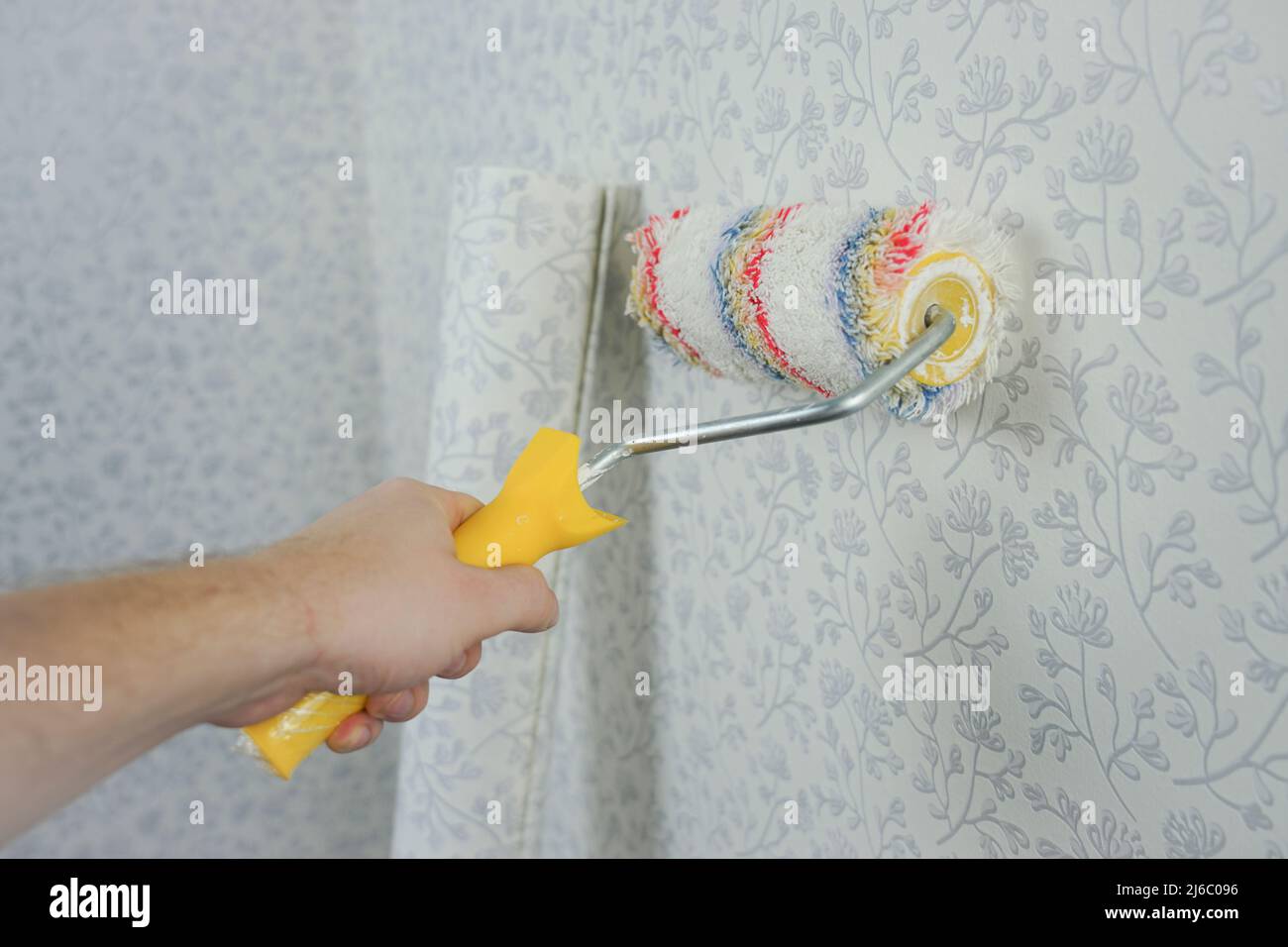 Hand holds a roller for painting the walls. Soft roller for wallpapering and textured application Stock Photo
