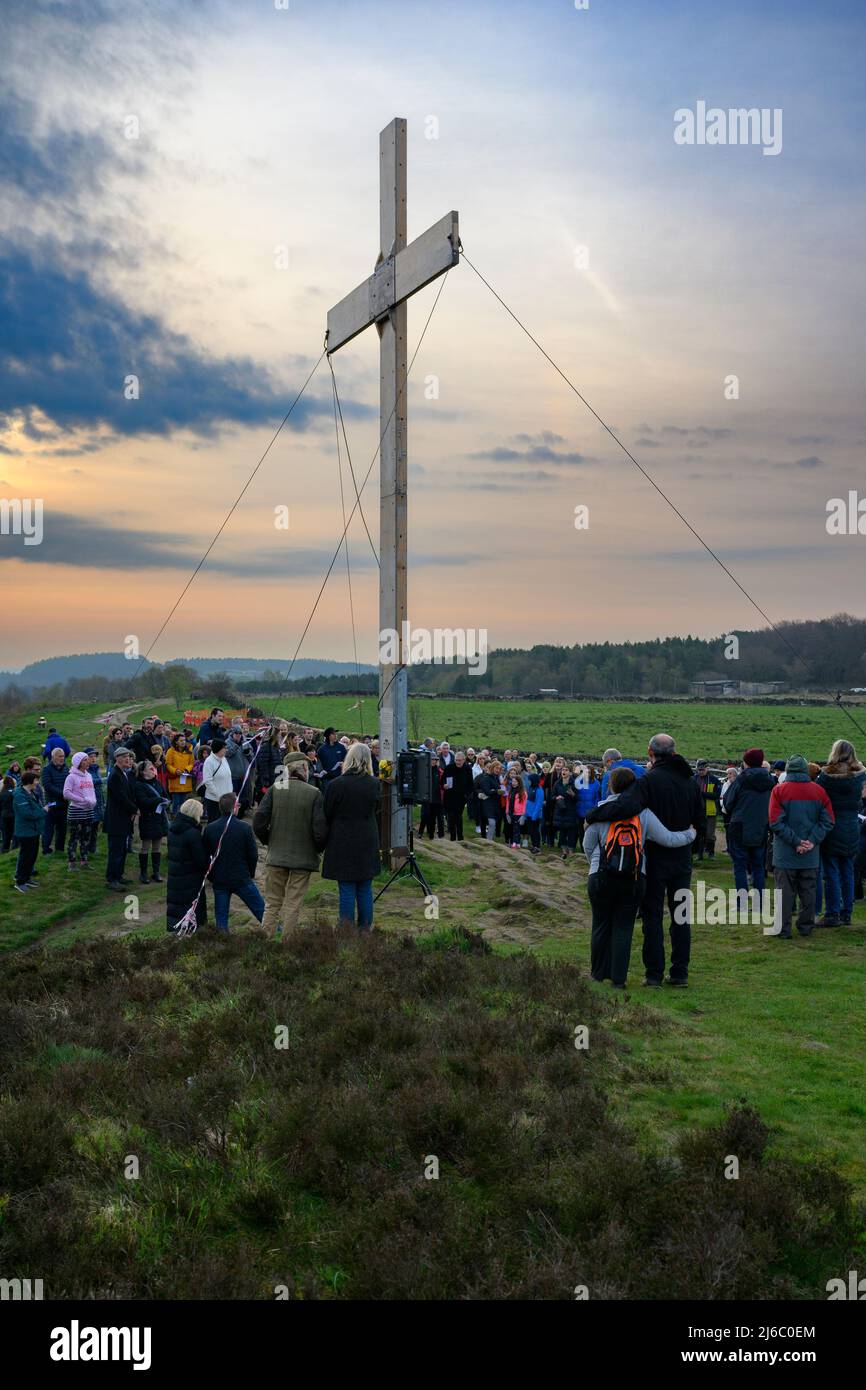 Congregation crowd gathered on hilltop for traditional Easter Sunday dawn service by high wooden cross - The Chevin, Otley, West Yorkshire England UK. Stock Photo
