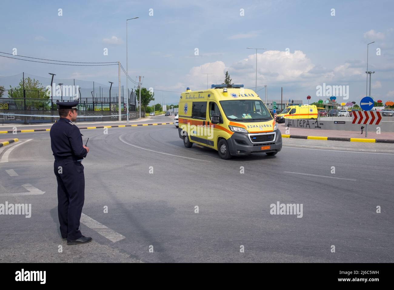 Police officer controlling the traffic with two ambulances following the cyclists in the 2022 International Tour of Hellas cycling race Stock Photo