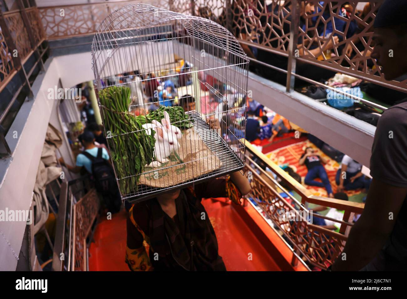A girl carries a cage with rabbits inside it as she gets onboard a passenger ferry to travel home to celebrate Eid al-Fitr, in Dhaka, Bangladesh, April 30, 2022. REUTERS/Mohammad Ponir Hossain Stock Photo