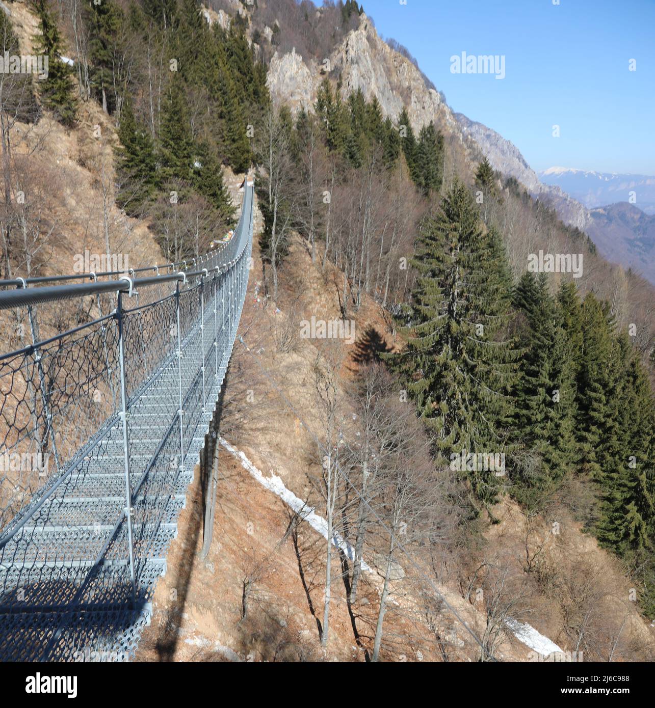 long suspension bridge over the valley between the mountains made with sturdy steel ropes Stock Photo