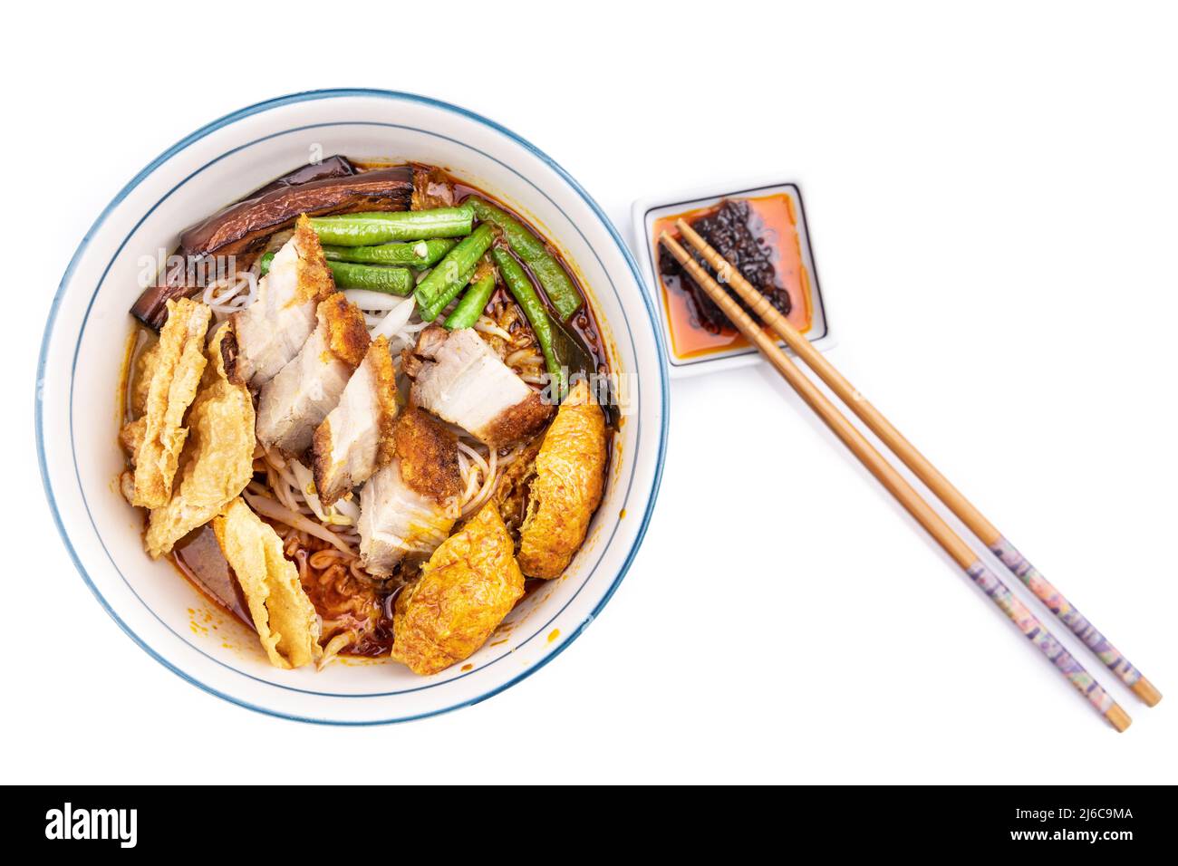 Curry mee or curry laksa is noodle served in curry broth made of cocunut milk, accompanied with roast pork, bean curd, vegetables. Stock Photo