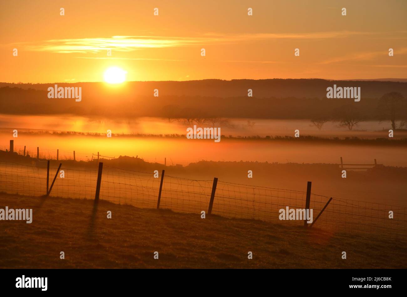 Sunset and low mist rolling over farm fields, near Culmaily, Sutherland, Scotland, UK. Stock Photo