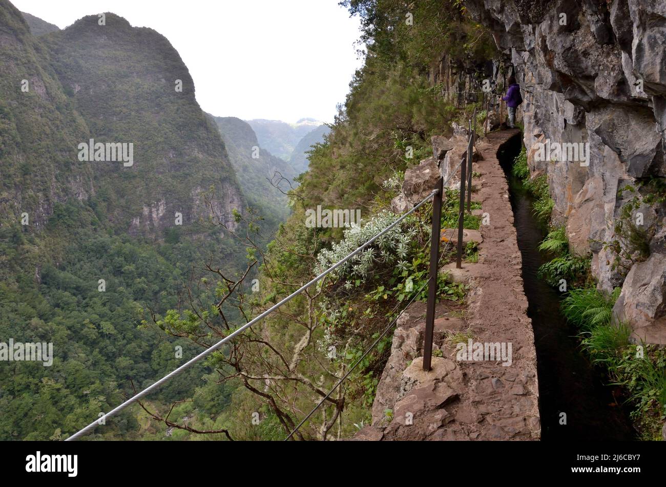 A Levada (irrigation channel) and narrow path on a very steep mountainside in Madeira, Portugal. Stock Photo