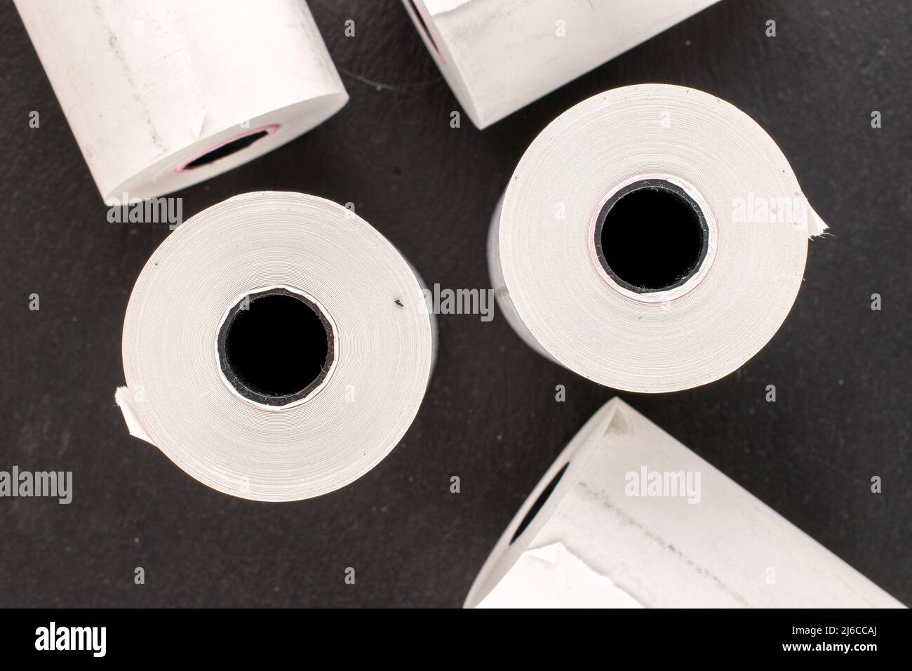 Several rolls of paper tape for a cash register on a slate stone, macro, top view. Stock Photo