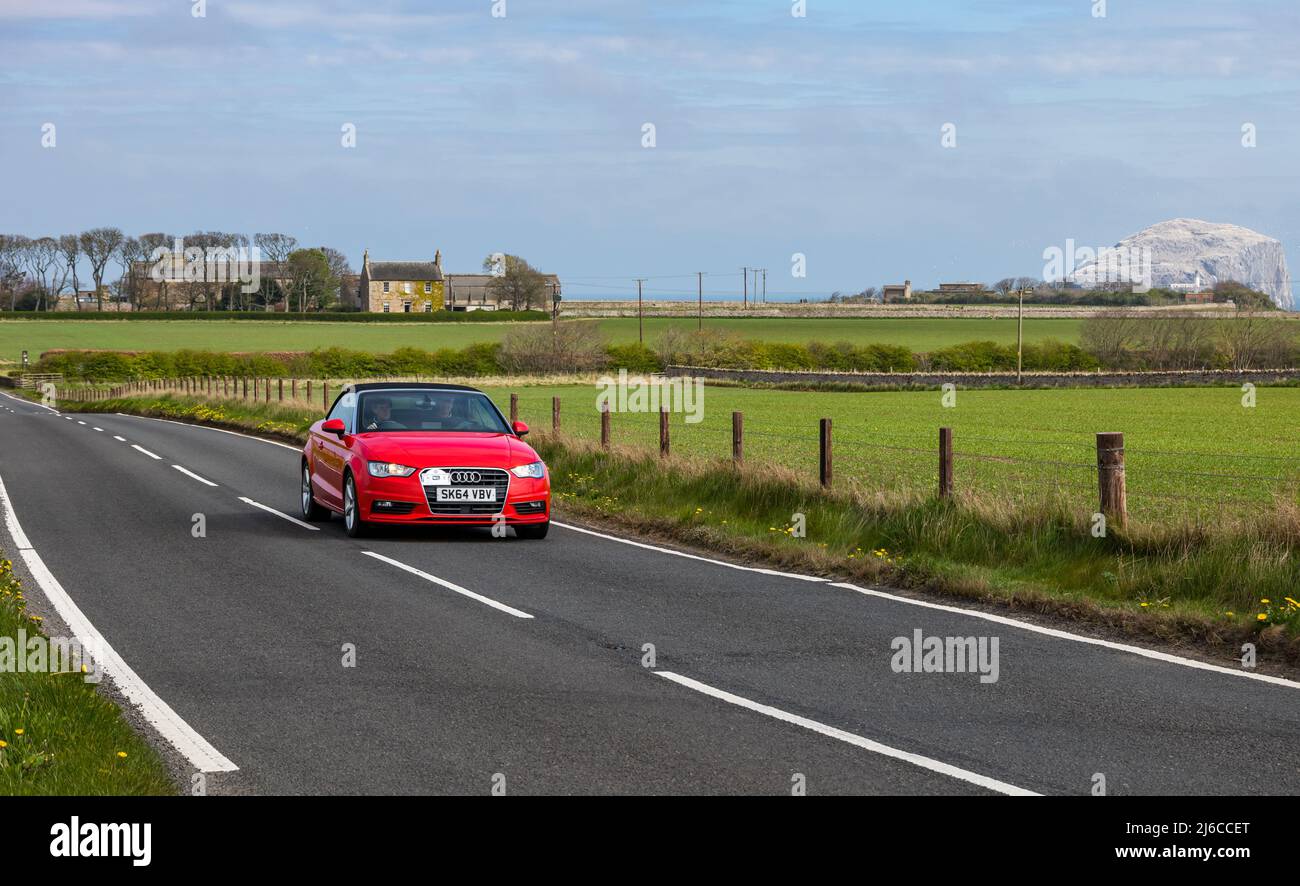 Red Audi convertible sports car driving on country coastal road by Bass Rock island, East Lothian, Scotland, UK Stock Photo