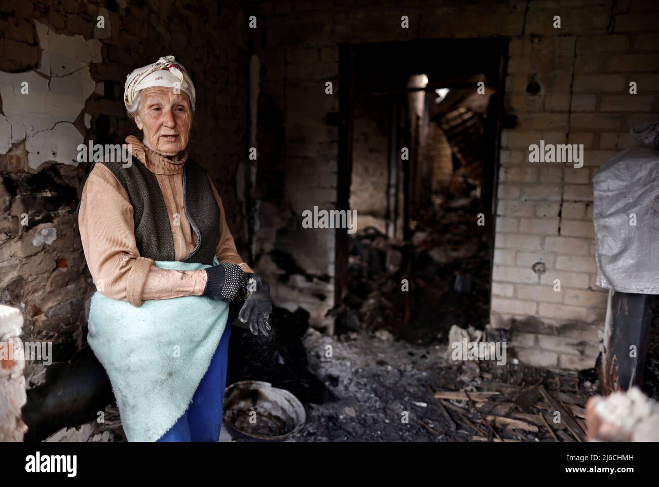 Hanna Selivon, 77, stands at her house, which according to her was destroyed by Russian shelling, amid their invasion of Ukraine, on the outskirts of Chernihiv, Ukraine April 30, 2022. Selivon said she now lives at the volunteer center in downtown Chernihiv and bikes everyday to her home to try to recover what remains of her belongings. REUTERS/Zohra Bensemra Stock Photo