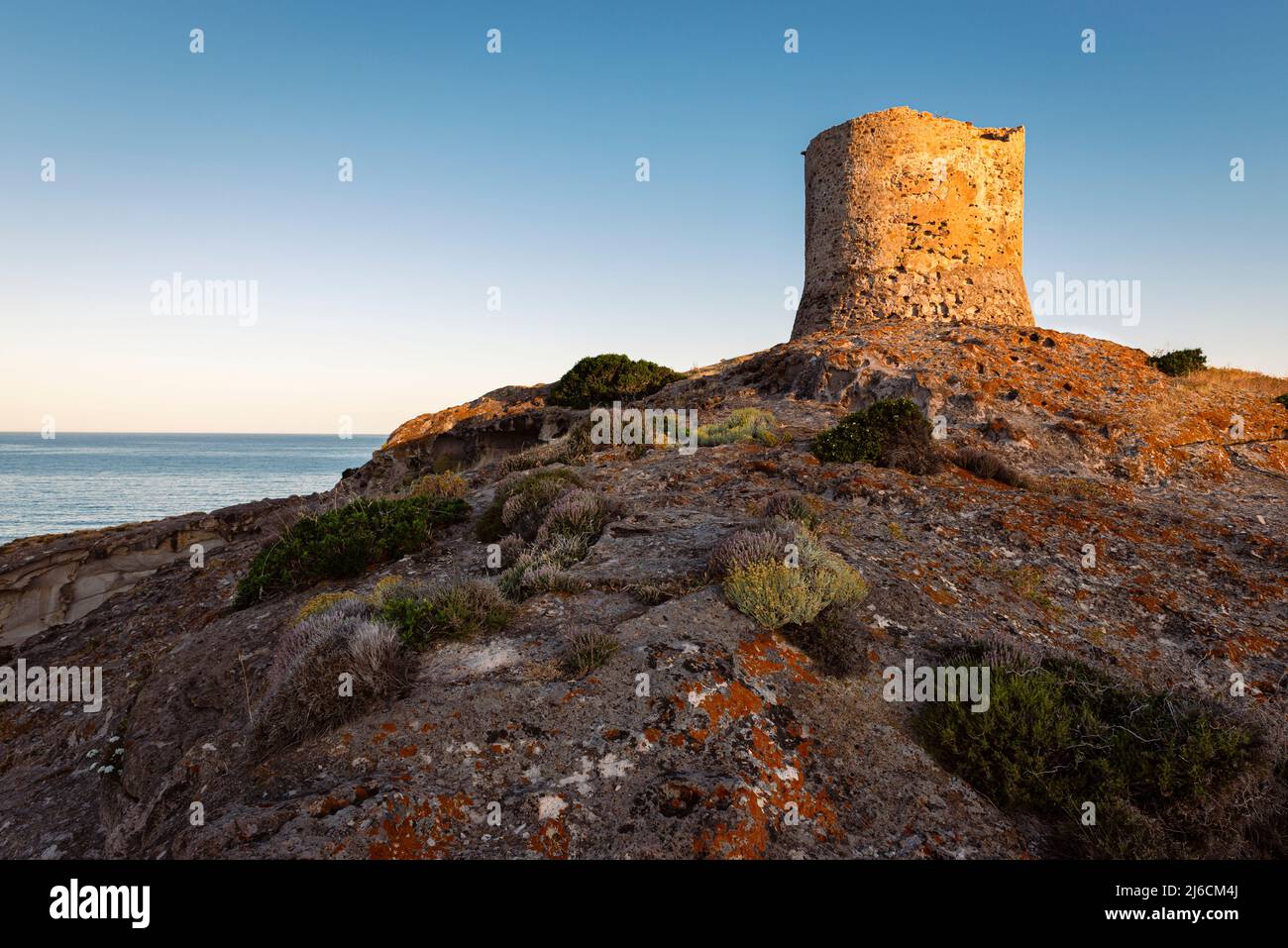 Nature experience - Ruins of the old coastal watchtower Torre Argentina on a rock above the west coast of Sardinia in the Mediterranean Sea at sunrise Stock Photo