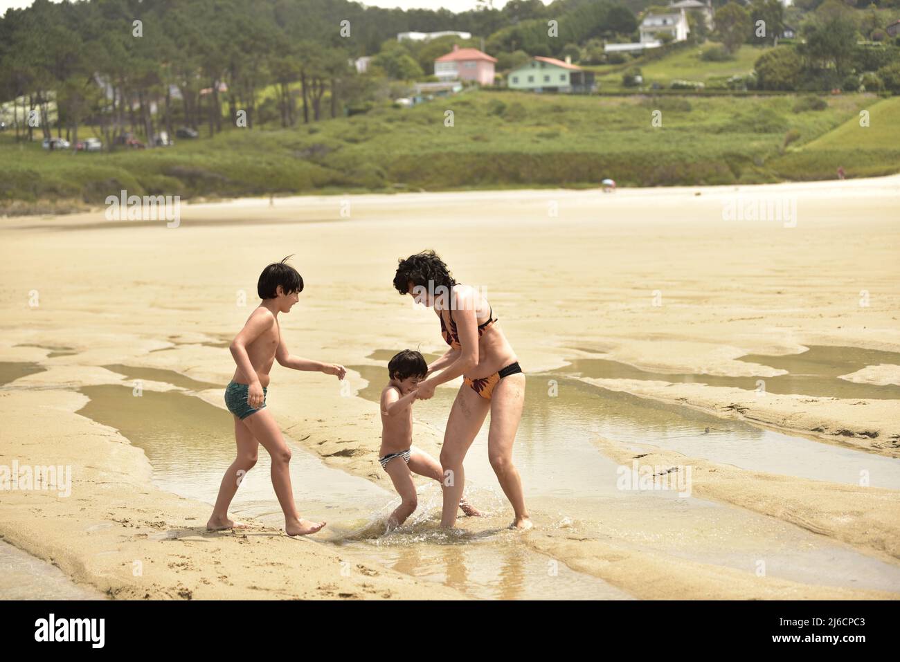 caucasian family plays at low tide on a beach Stock Photo