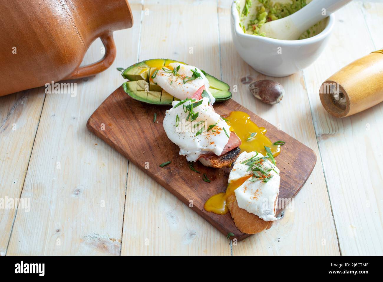 three poached eggs on bread with ham , guacamole, and other ingredients ...