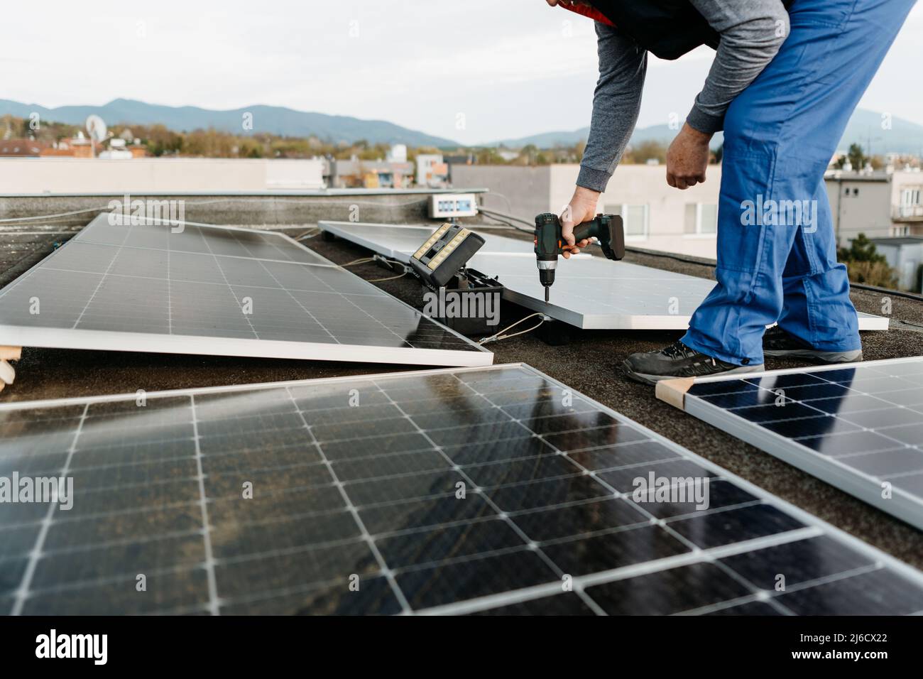 Man worker installing solar photovoltaic panel system using screwdriver. Alternative energy concept Stock Photo