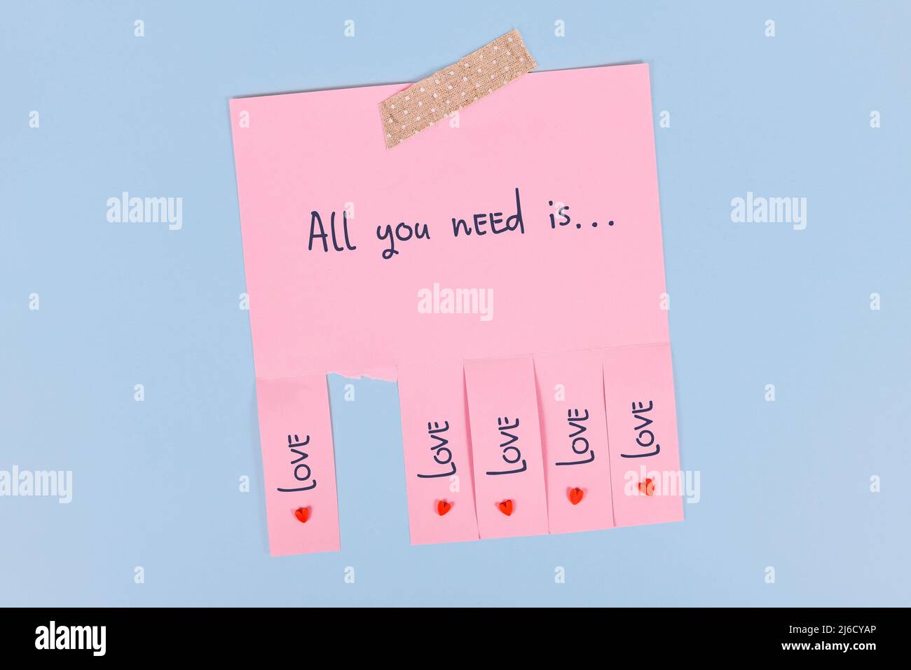Tear off stub note with text 'All you need is love' on pink paper Stock Photo