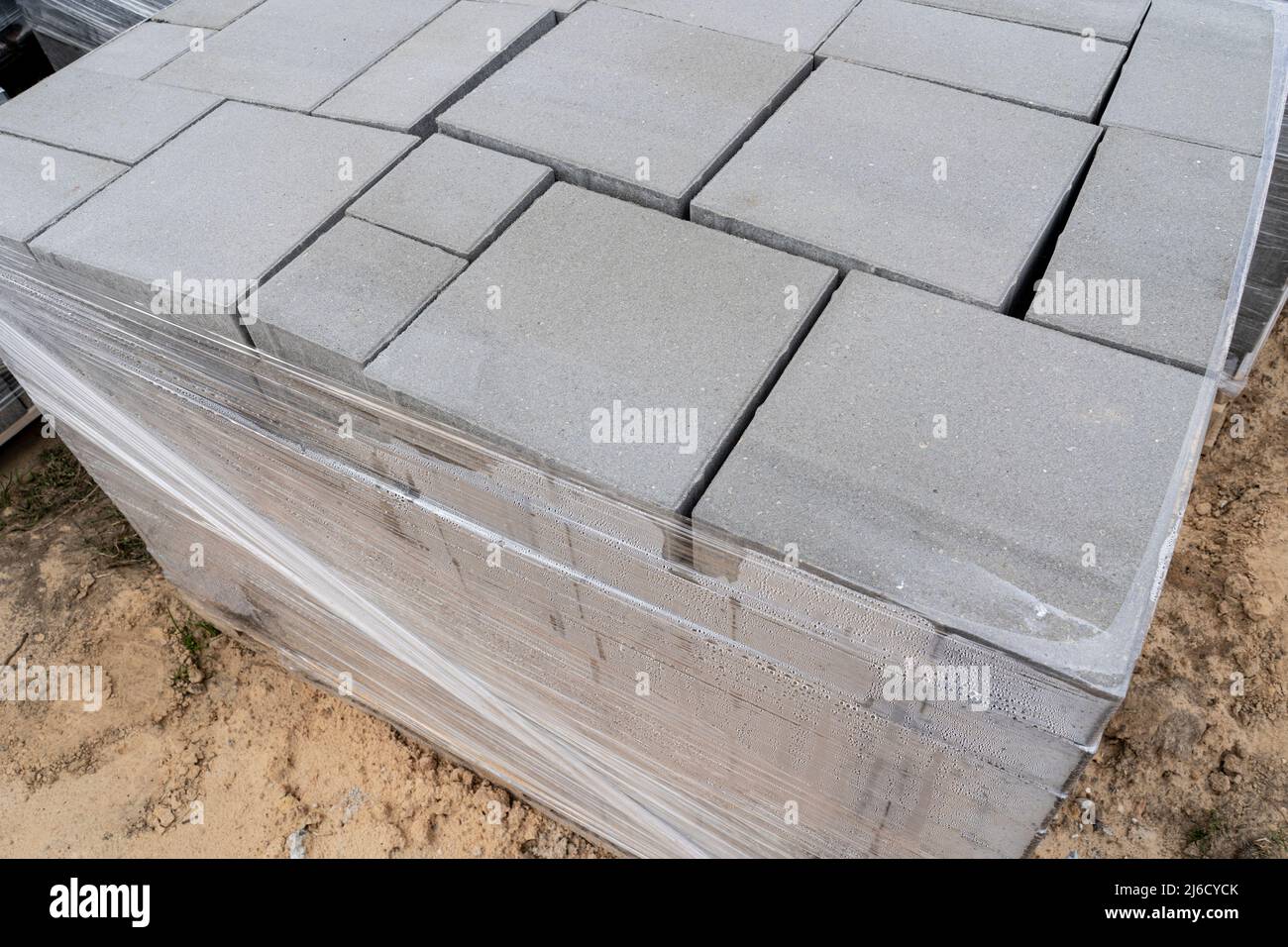 Laying of gray concrete paving slabs in the house courtyard driveway