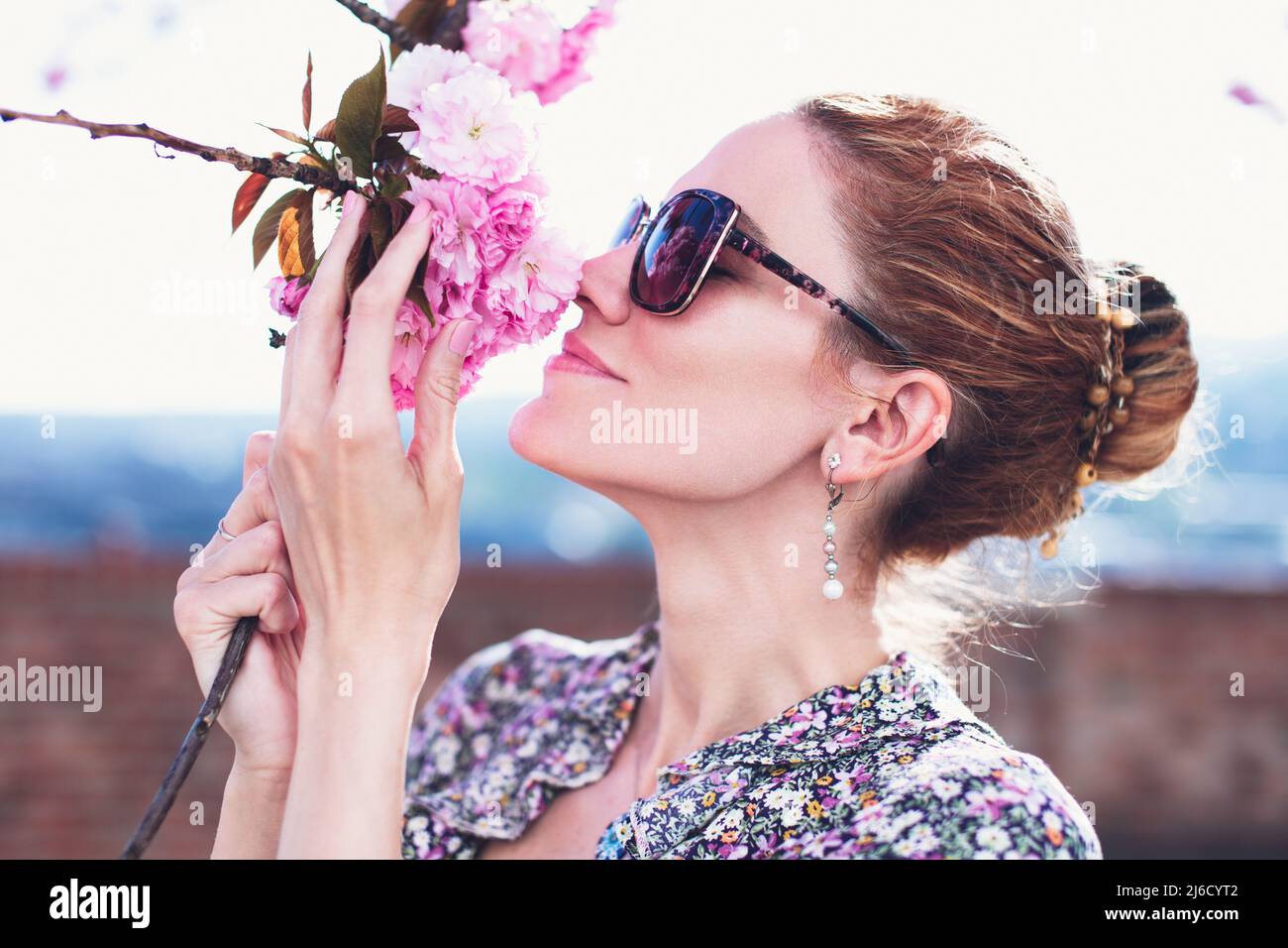 Young redhead woman smelling cherry blossom at springtime portrait Stock Photo