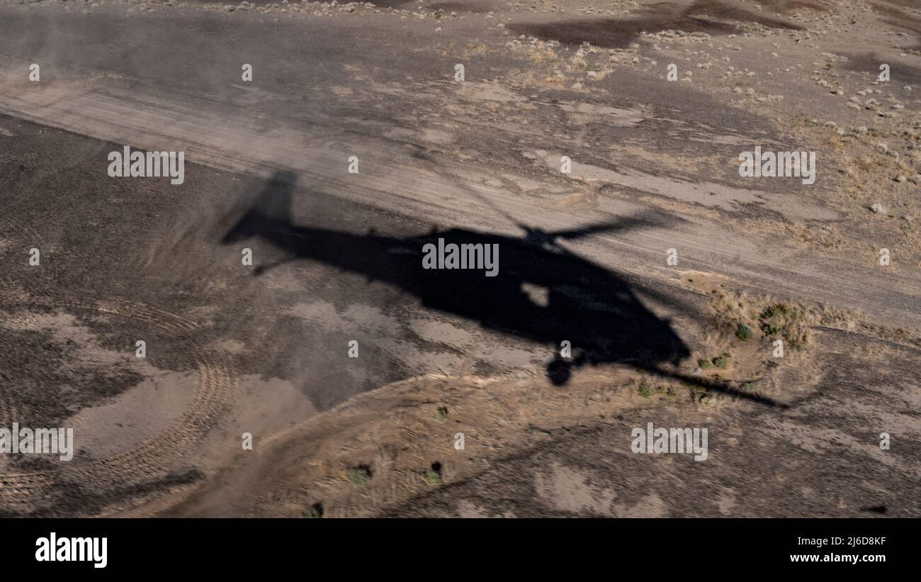 A HH-60G Pave Hawk combat search and rescue (CSAR) helicopter hovers over the ground while being piloted by Captain Garret Wells and 1st Lieutenant William Leshley, 66th Rescue Squadron, April 28, 2022, in North Las Vegas, Nevada. Pave Hawk mission equipment includes a retractable in-flight refueling probe, internal auxiliary fuel tanks, two crew-served 7.62mm or .50 caliber machineguns, and an 8,000-pound (3,600 kilograms) capacity cargo hook. To improve air transportability and shipboard operations, all HH-60Gs have folding rotor blades.  (U.S. Air Force photo by Tech. Sgt. Alexandre Montes) Stock Photo