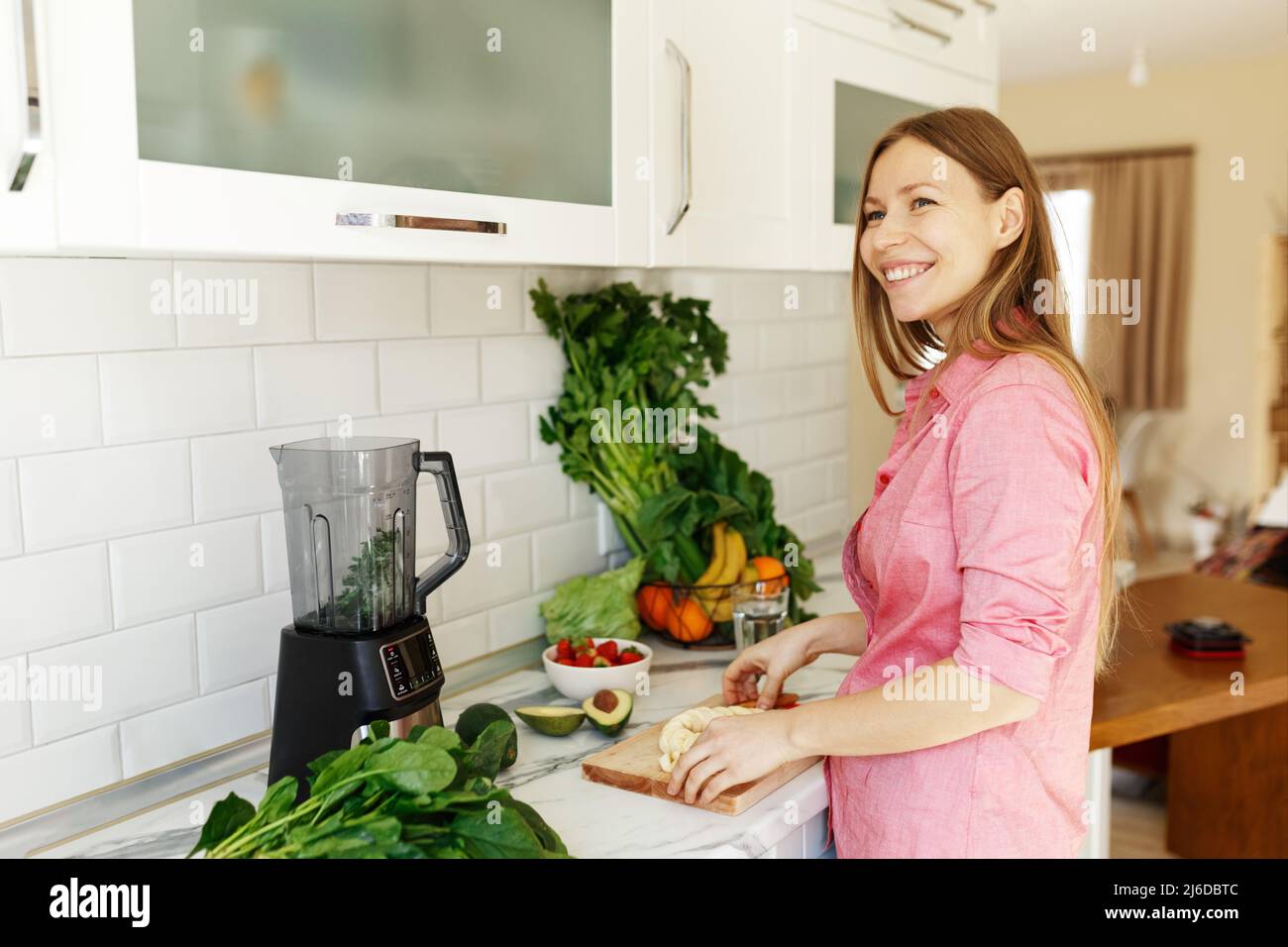 Portrait of beautiful woman chopping fruits smoothies with blender