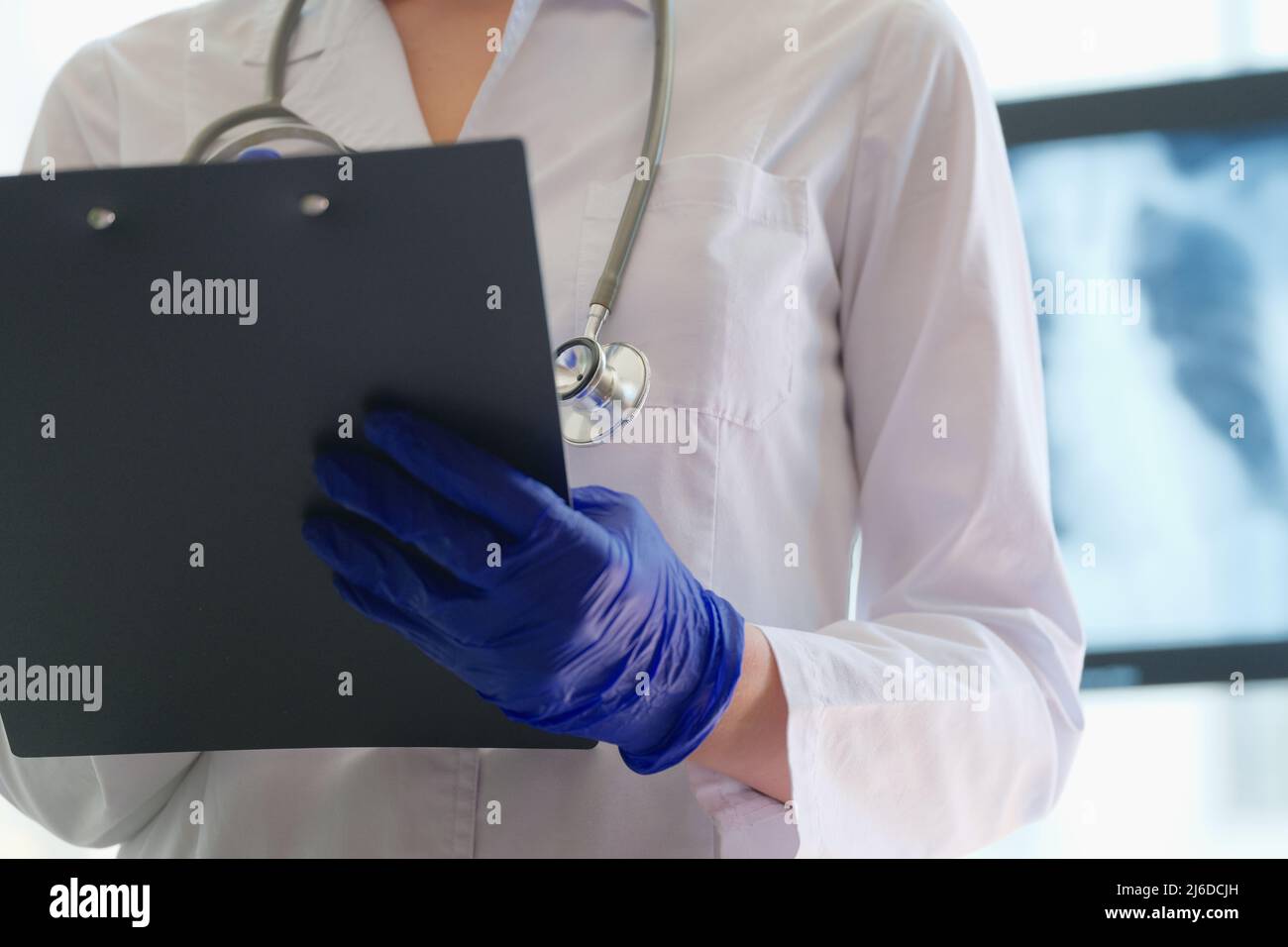 Radiologist checks xray image and holds clipboard in hands Stock Photo