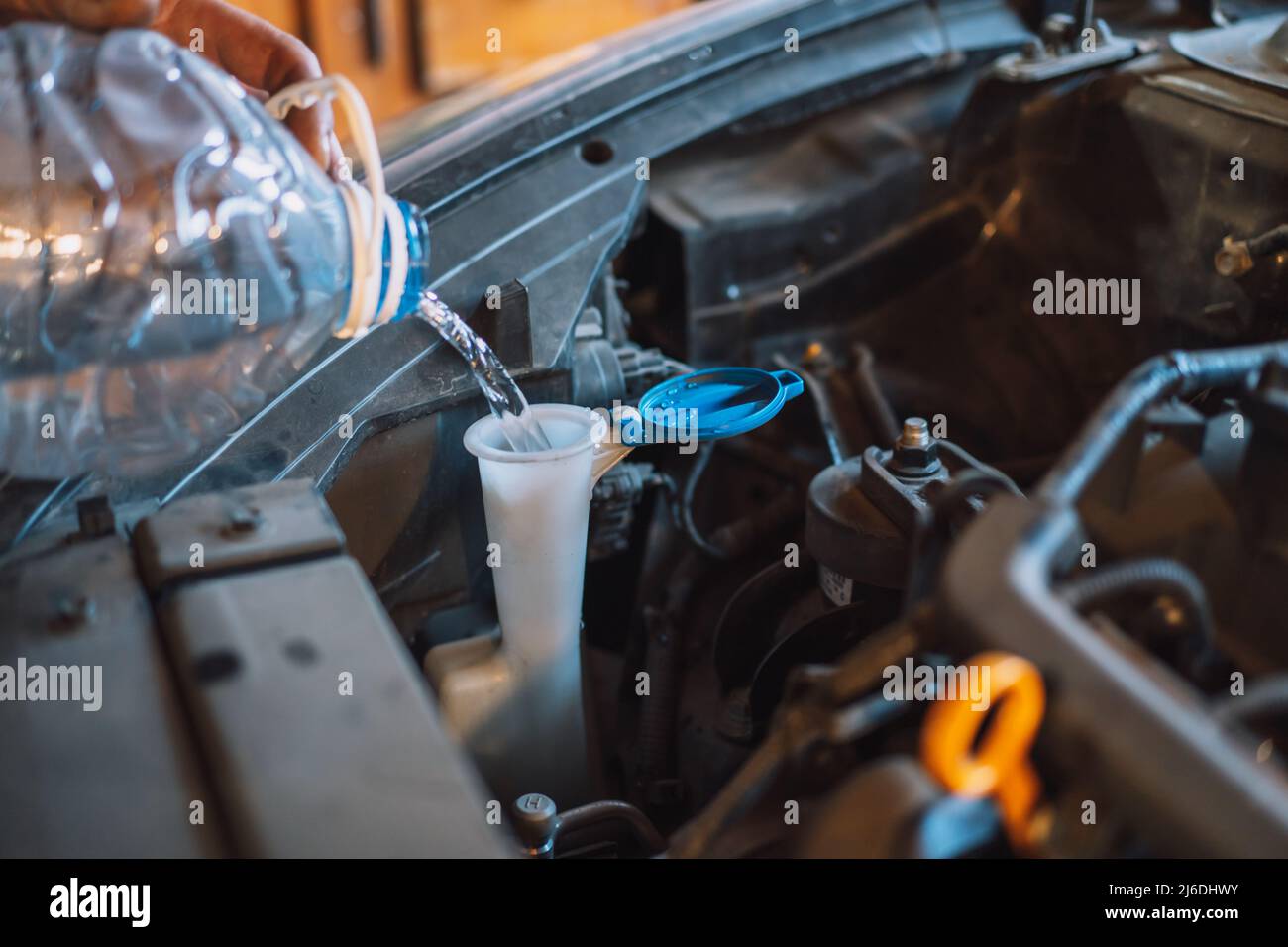 Mechanic pouring water into the windshield washer reservoir Stock Photo