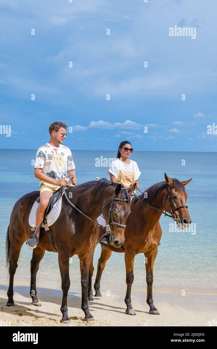 horse riding on the beach, man and woman on a horse on the beach during
