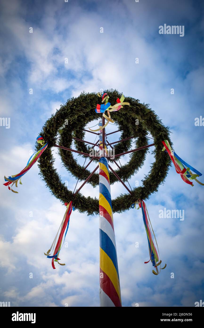 a colorfully decorated maypole in nice weather and the sky is blue ...