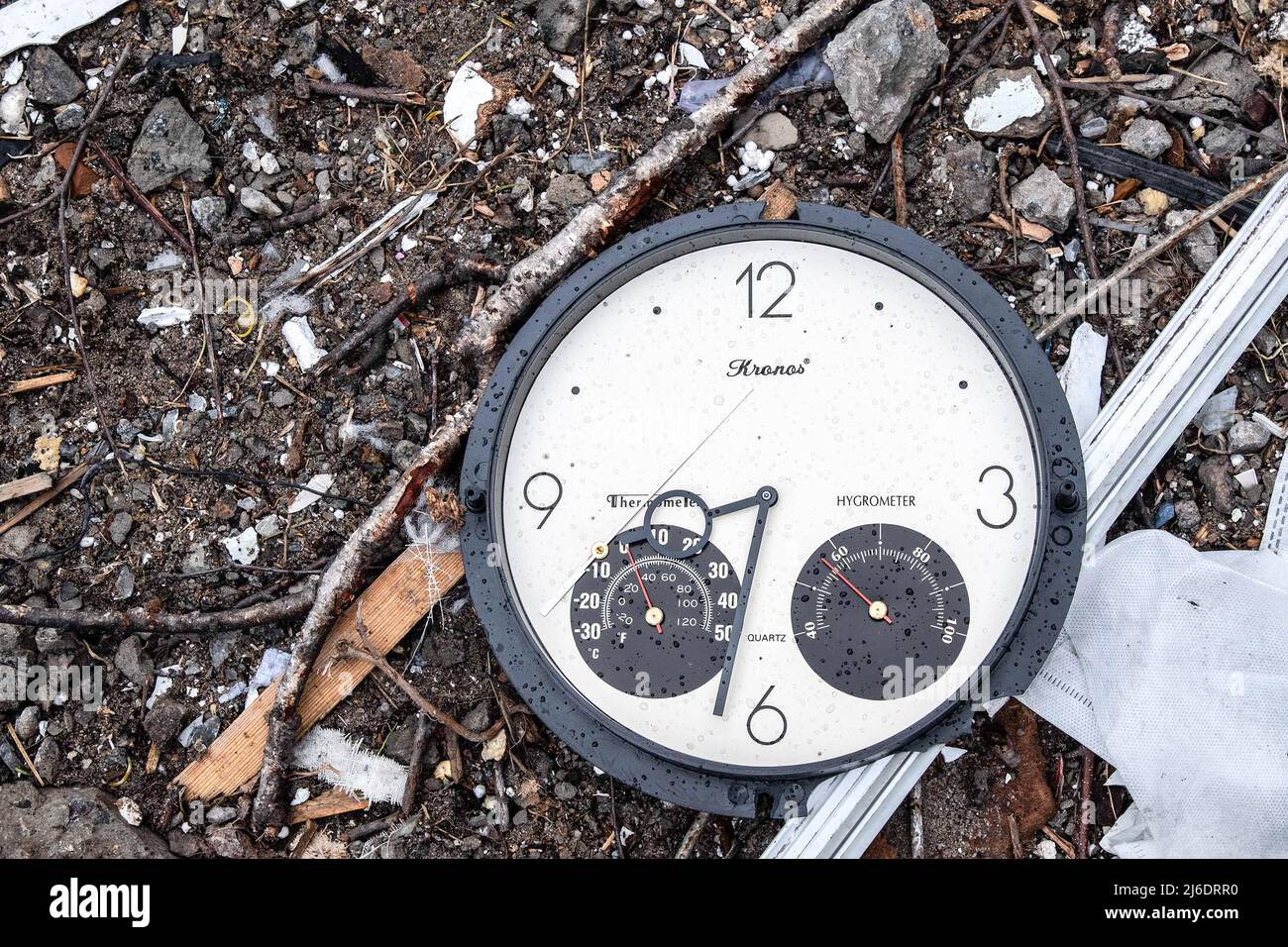 A clock rests on the ground among debris of a destroyed building ...