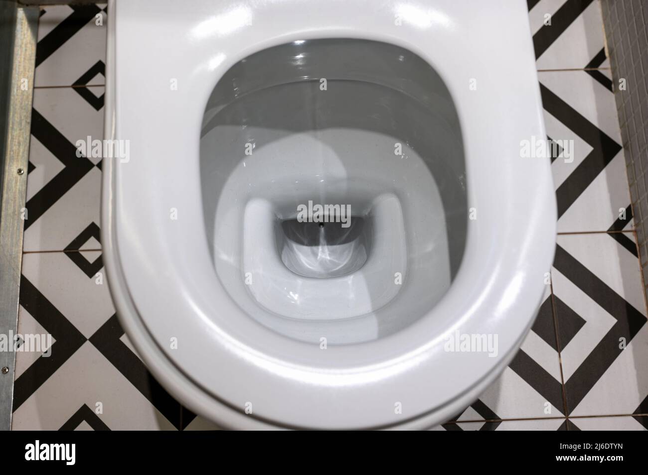 Close up view of white ceramic toilet in modern bathroom. Open toilet
