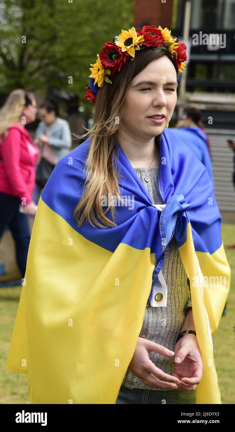 Manchester, UK, 30th April, 2022. A woman wears a Ukrainian flag. Protest about the Russian invasion of Ukraine in Piccadilly Gardens, central Manchester, England, United Kingdom, British Isles. It was organised by the Ukrainian Cultural Centre 'Dnipro' Manchester. More than 500 children have been killed or injured since Russia launched its invasion. Credit: Terry Waller/Alamy Live News Stock Photo