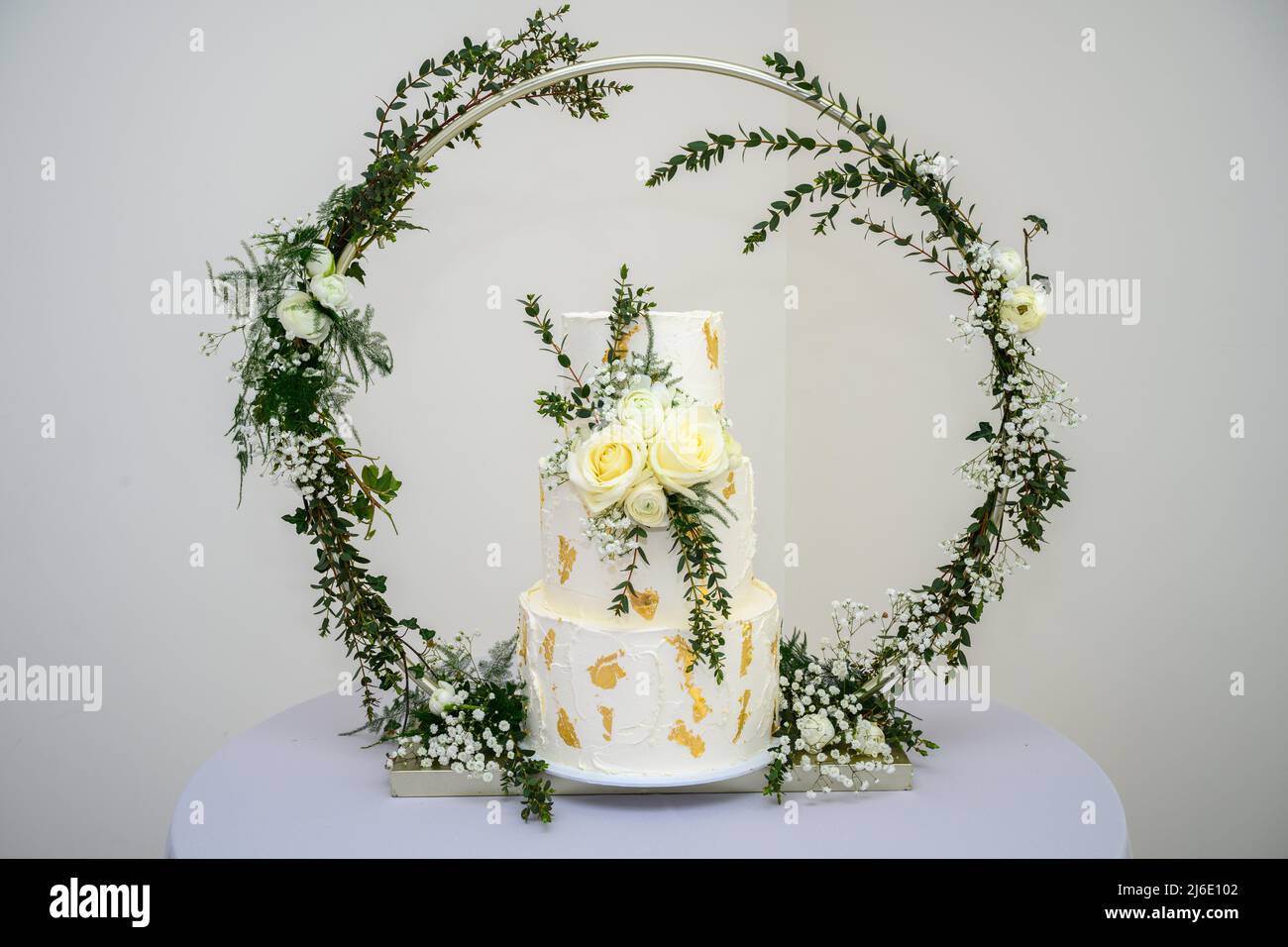 Three tier wedding cake with gold leaf and fresh flowers Stock Photo ...