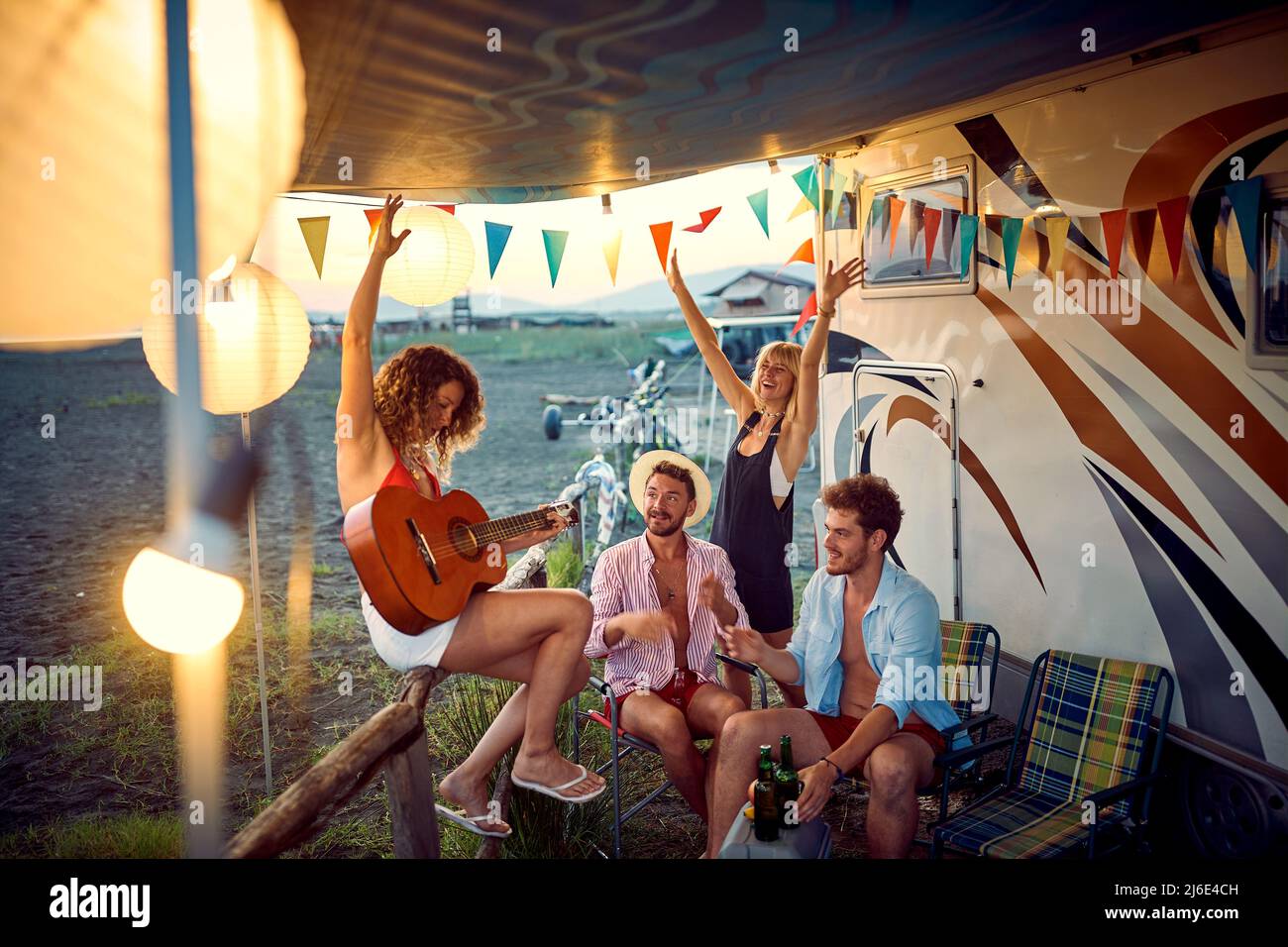 Happy friends in front of camper rv cheering with drinks have party ...