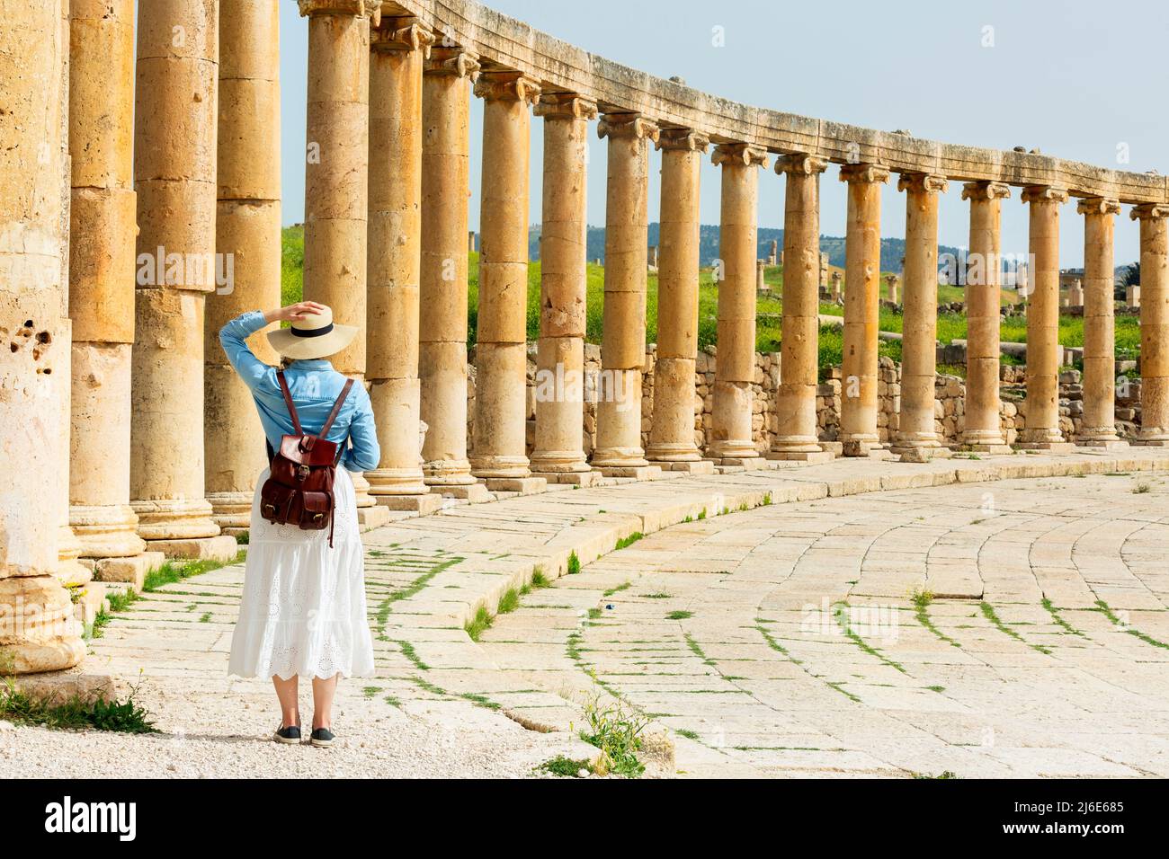 young woman tourist in color dress and hat leading man to South gate of the Ancient Roman city of Gerasa, modern Jerash, Jordan. Traveling together. F Stock Photo