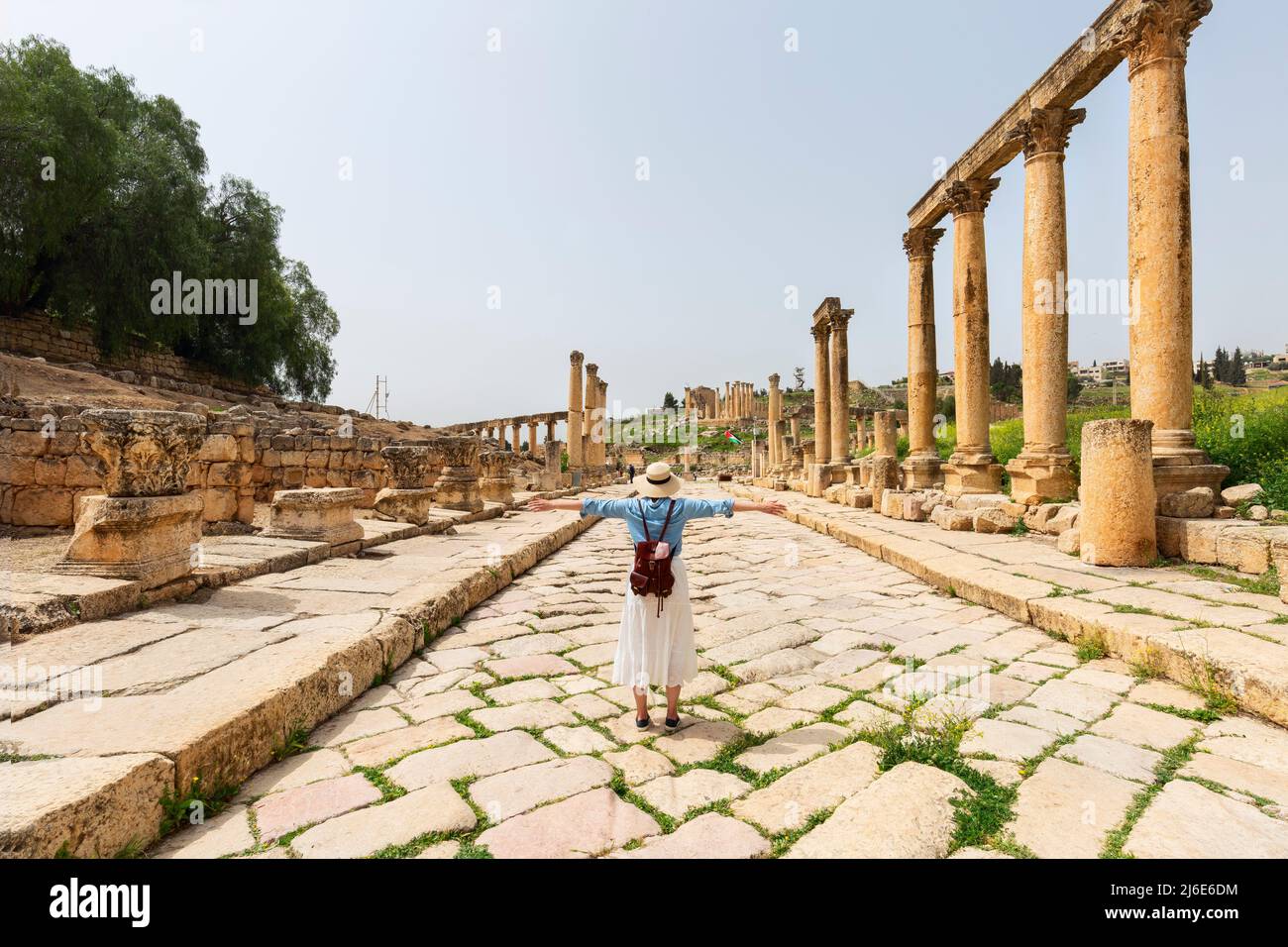 young woman tourist in color dress and hat leading man to South gate of the Ancient Roman city of Gerasa, modern Jerash, Jordan. Traveling together. Stock Photo