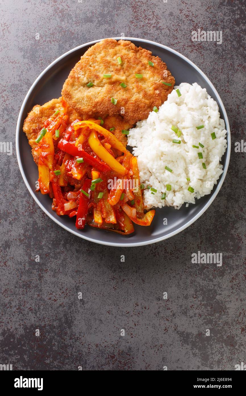 German schnitzel served with paprika sauce and rice closeup in a plate
